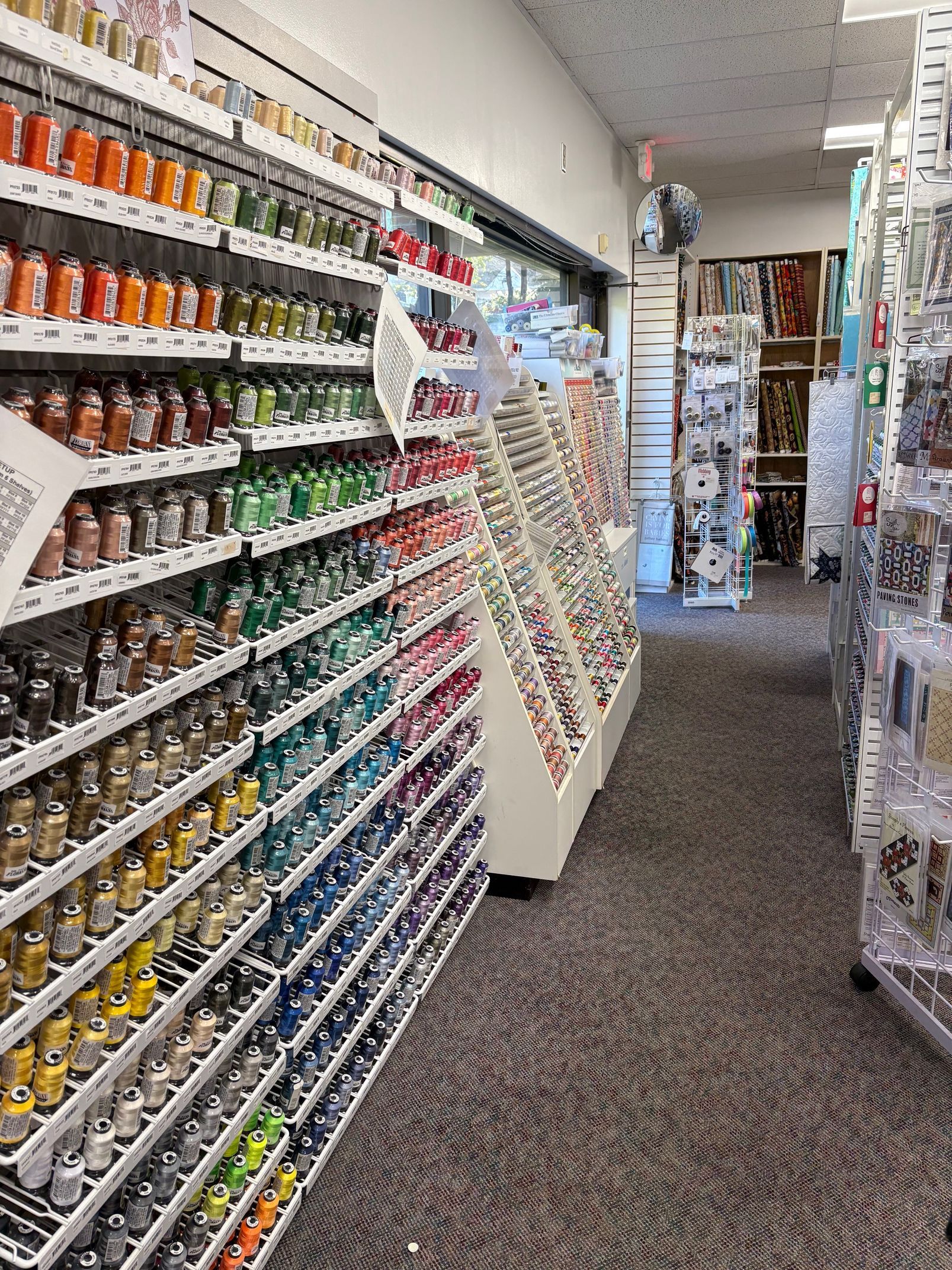 Rows of colorful craft supplies on shelves in a store. Brown and grey carpet.