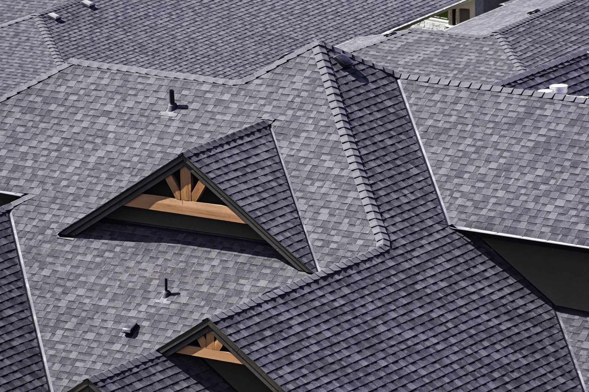 Dark gray shingled roof with multiple gables and a small dormer vent.