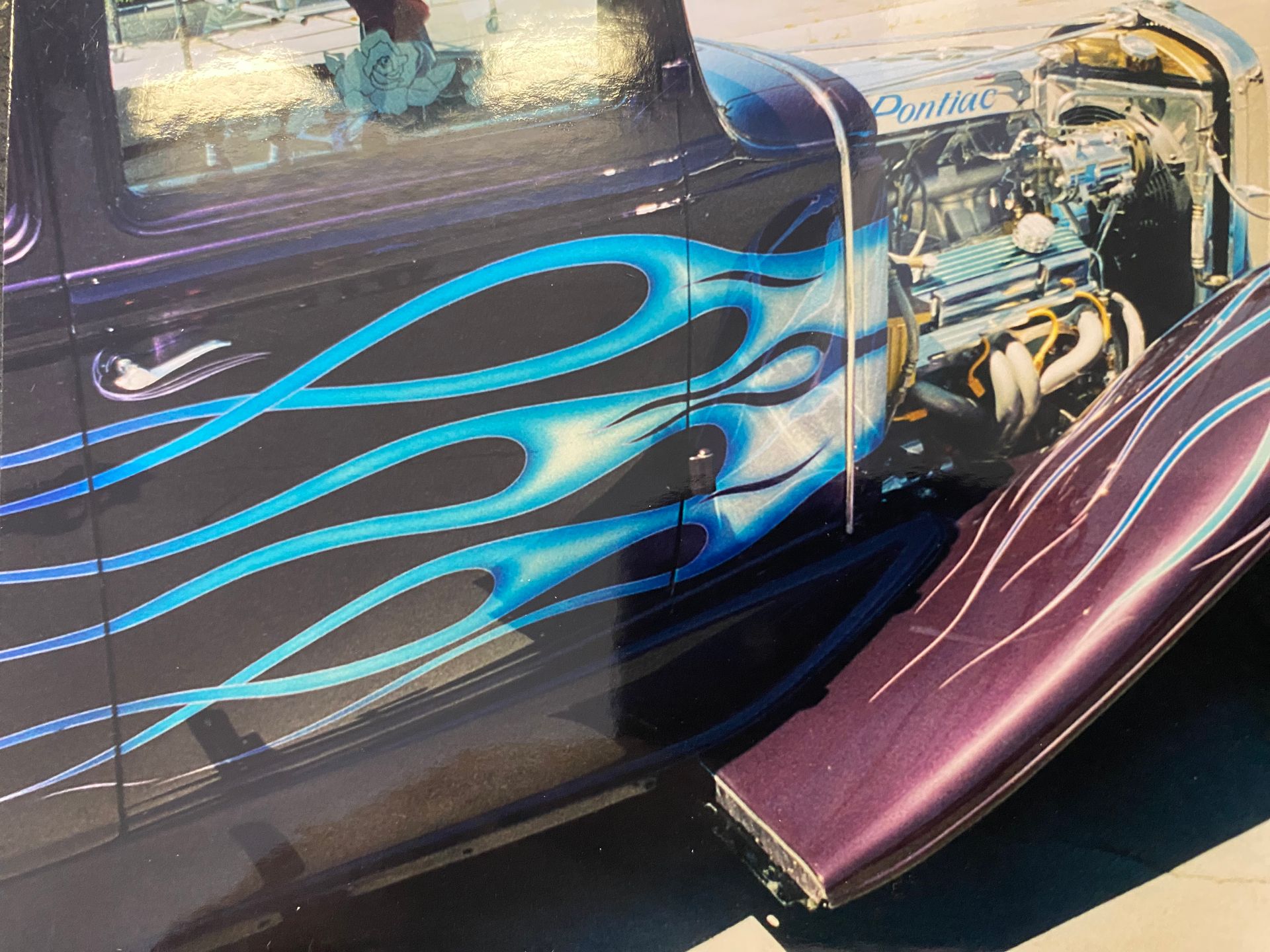 Classic black car with blue flames painted on the side and a visible engine.
