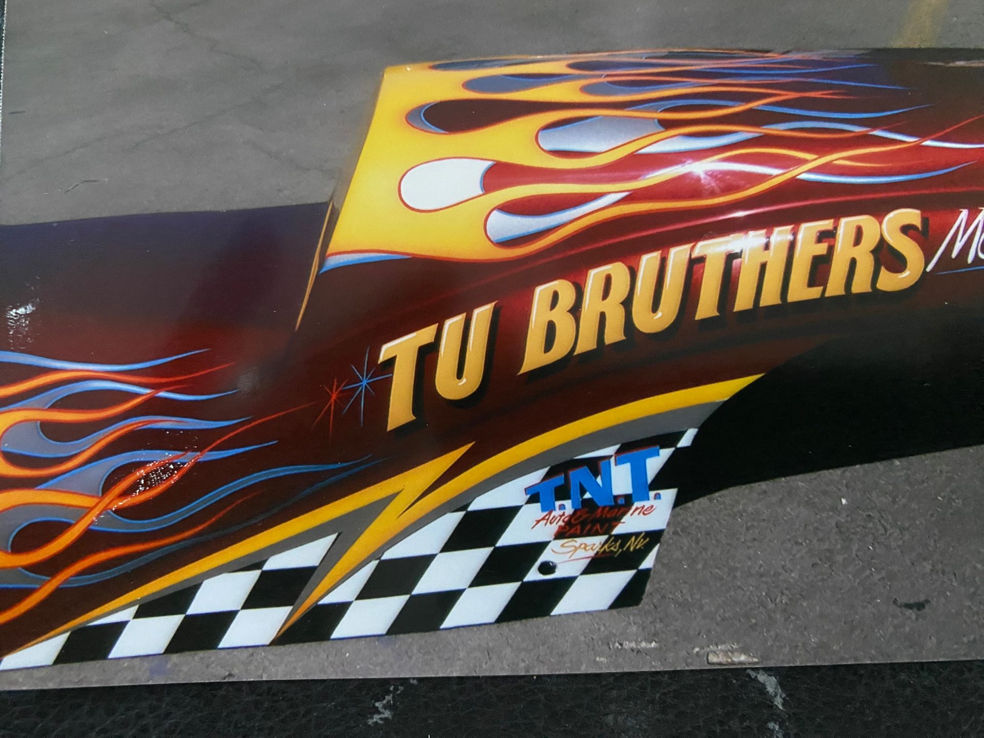 Race car with flames and TU BROTHERS logo, a checkered flag graphic, and TNT logo.