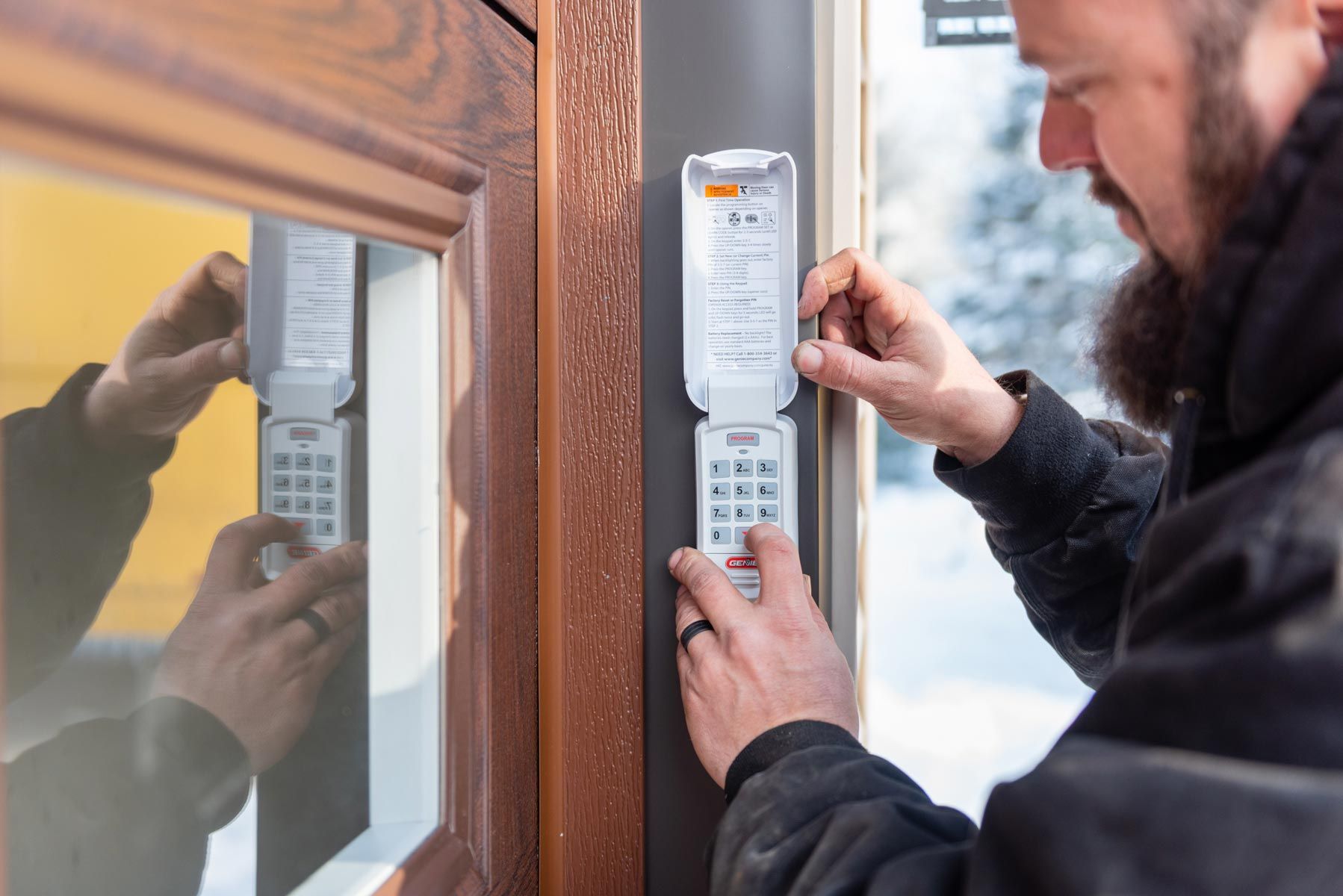 A man is installing a security system on a door.