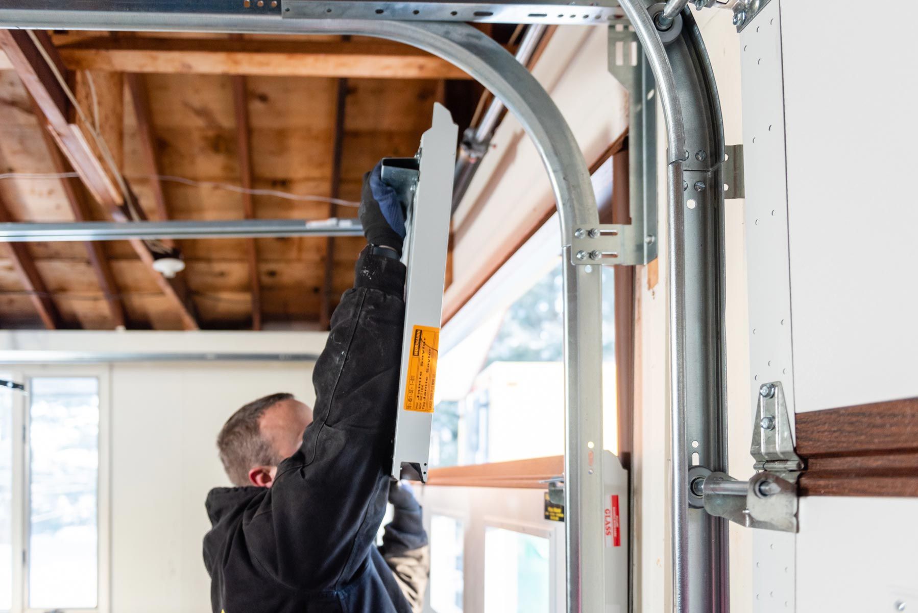 A man is installing a garage door in a garage.