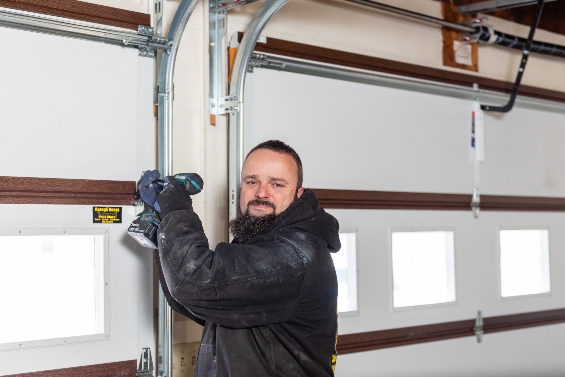 A man is installing a garage door with a drill.