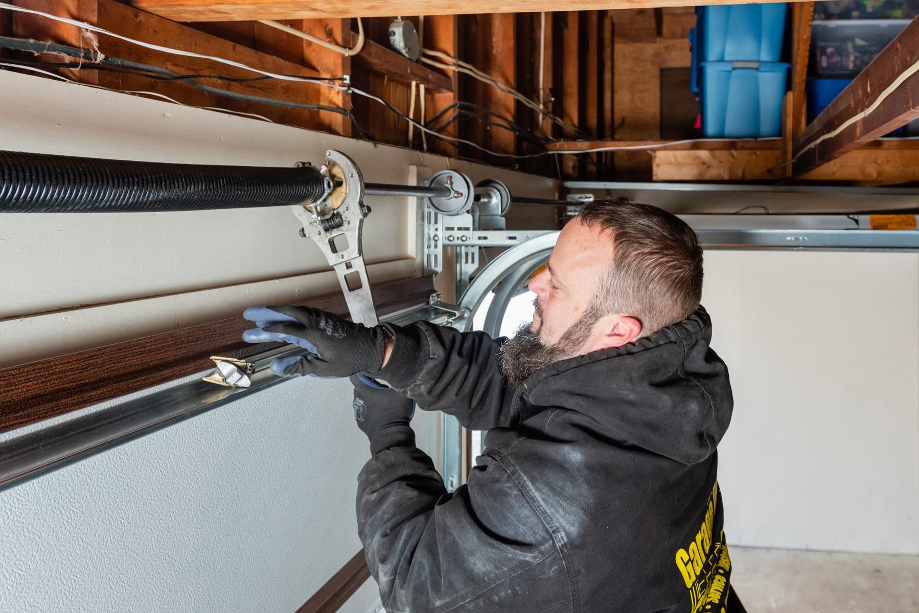 A man is fixing a garage door spring in a garage.