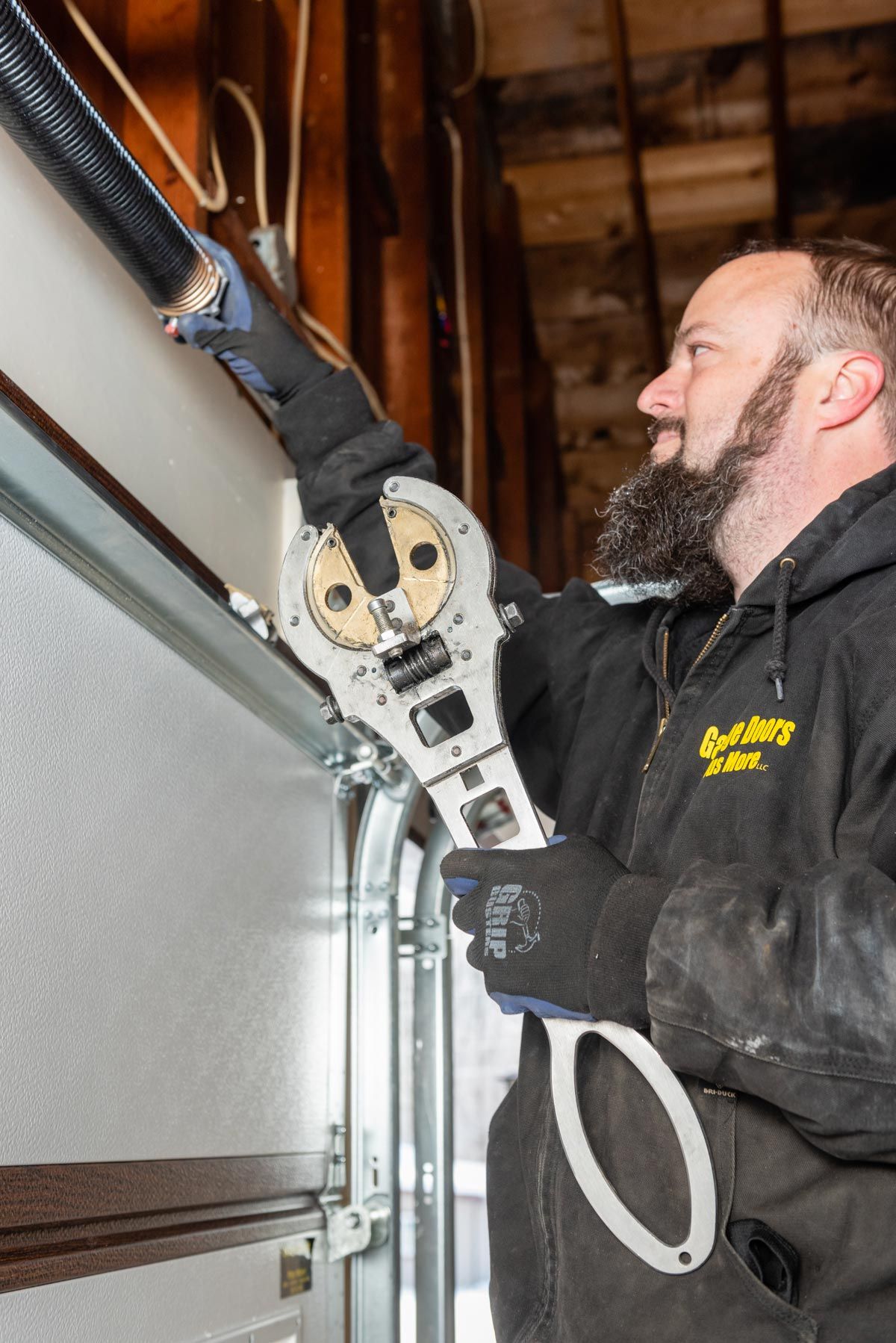 A man is working on a garage door with a wrench.