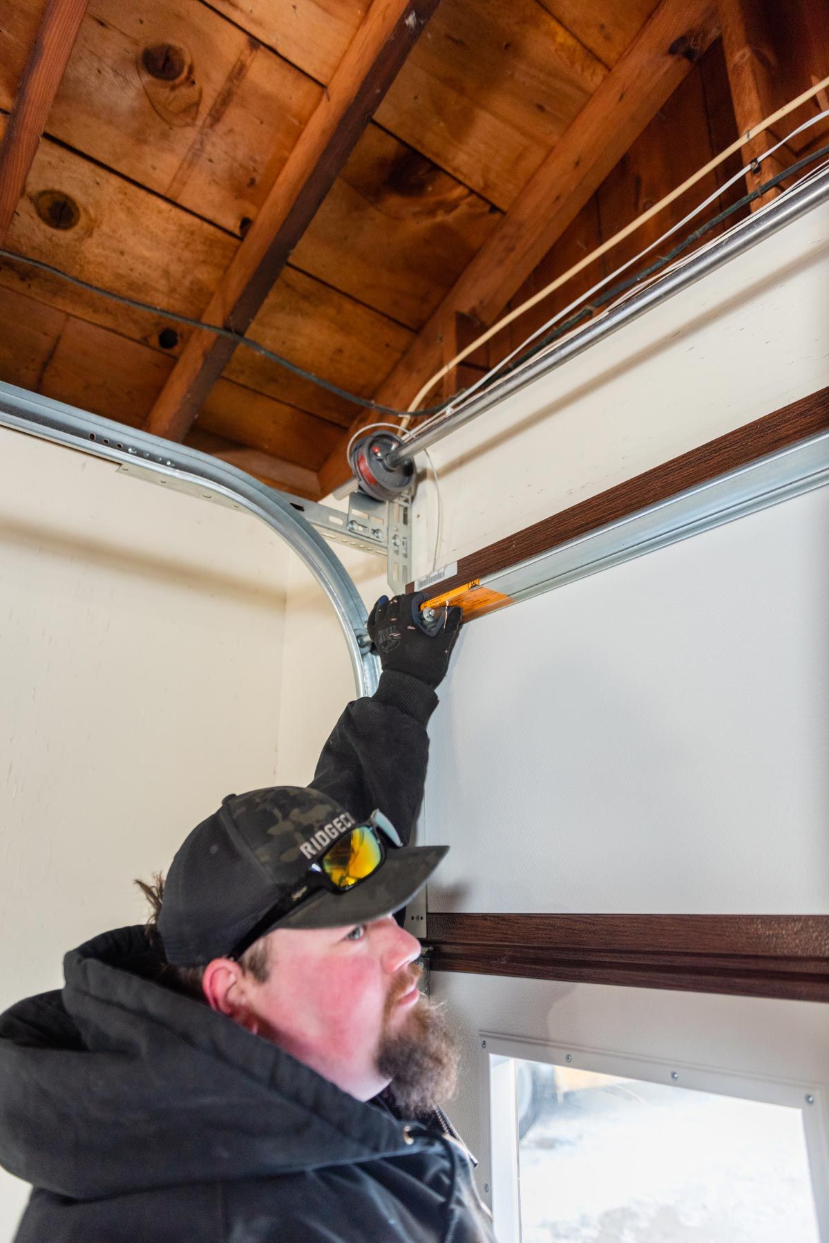 A man is fixing a garage door with a screwdriver.