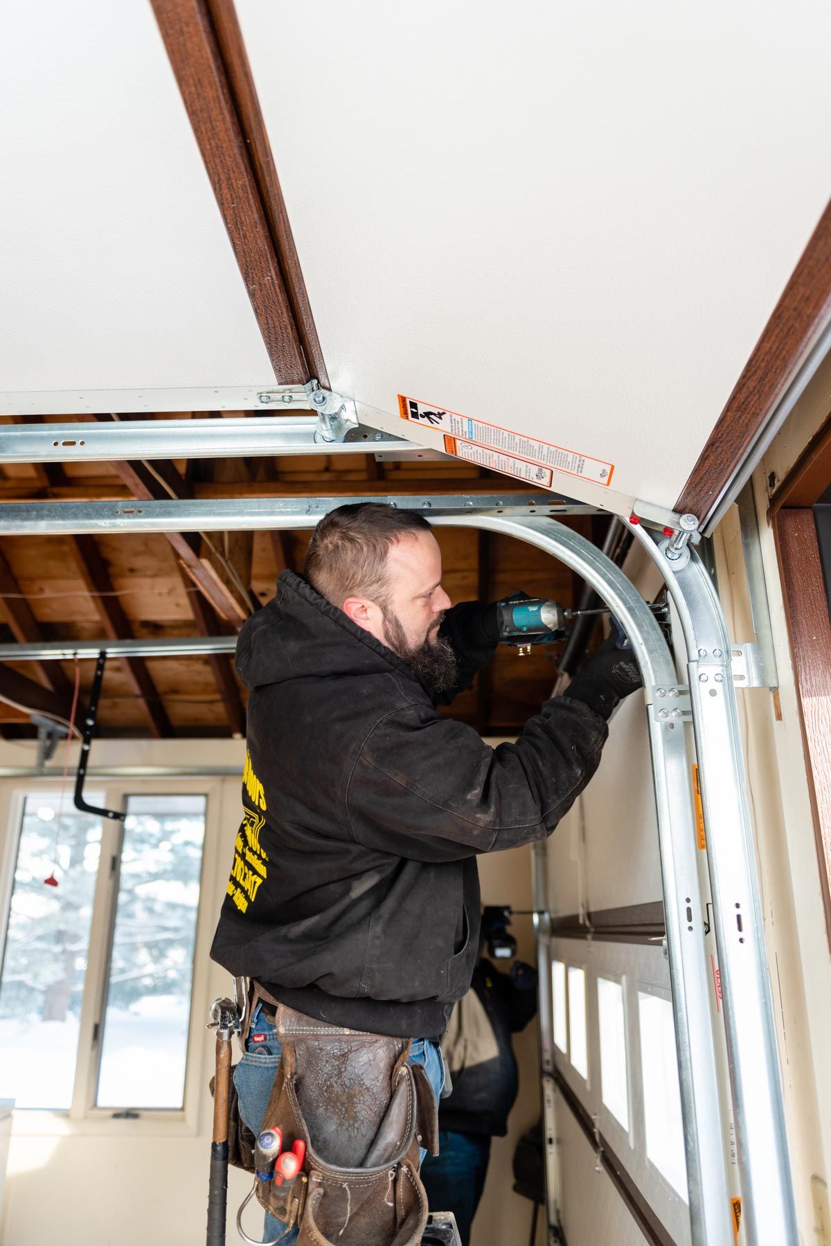 A man is working on a garage door in a garage.