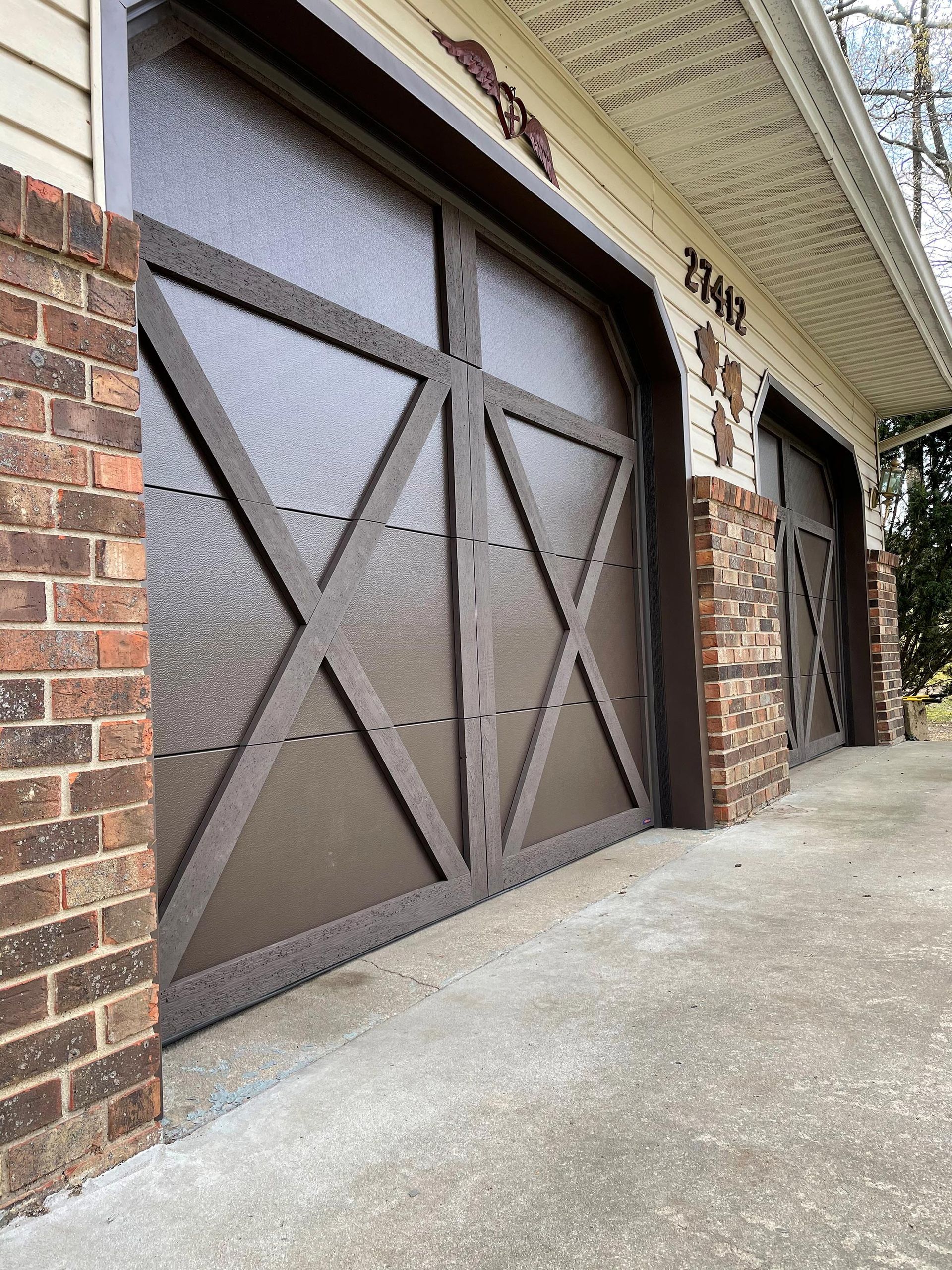 A garage door with a brick wall and a concrete walkway.