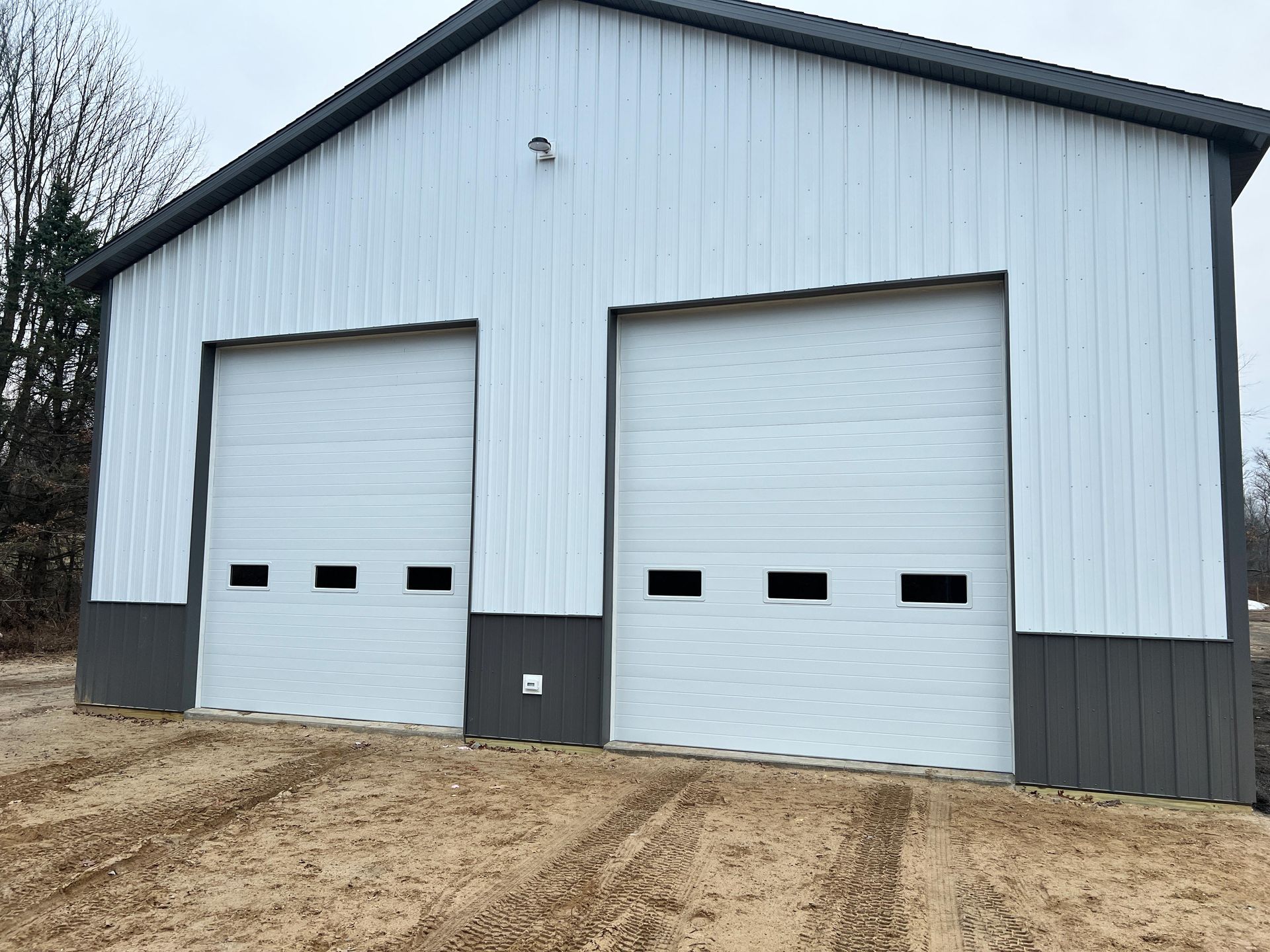 A white and gray metal building with two garage doors.
