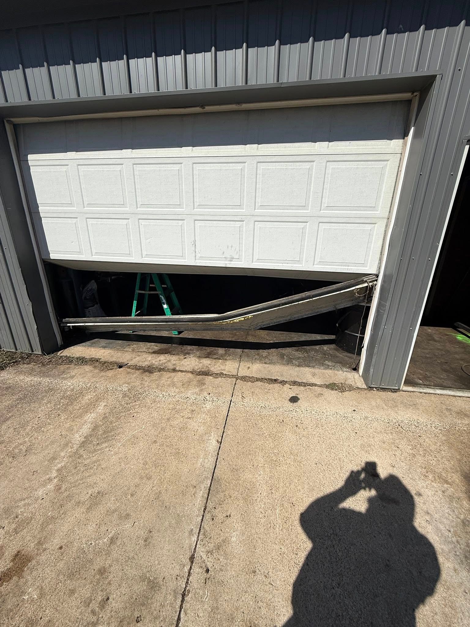 A person is taking a picture of a broken garage door.
