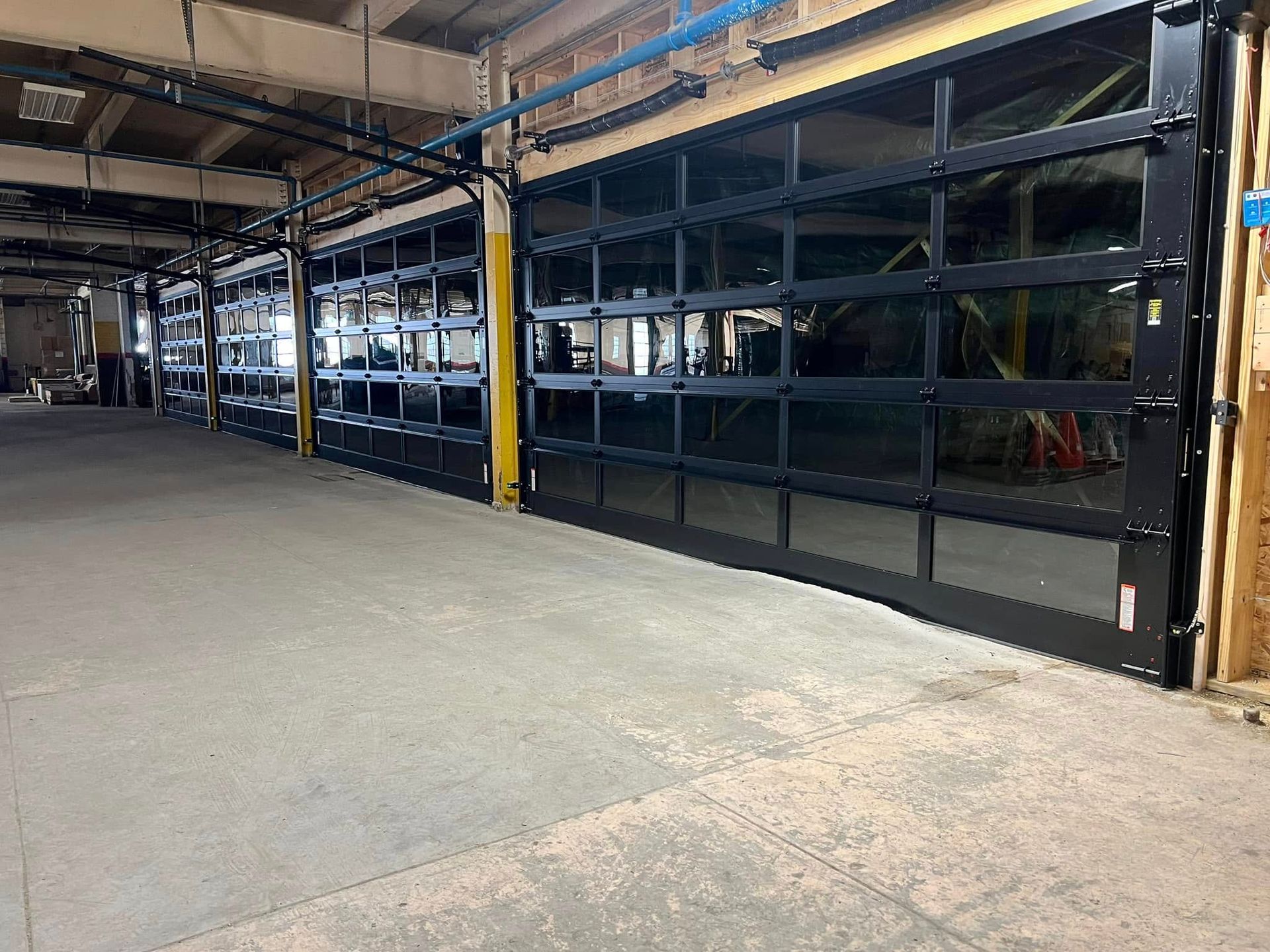 A row of garage doors in a building with a lot of windows.