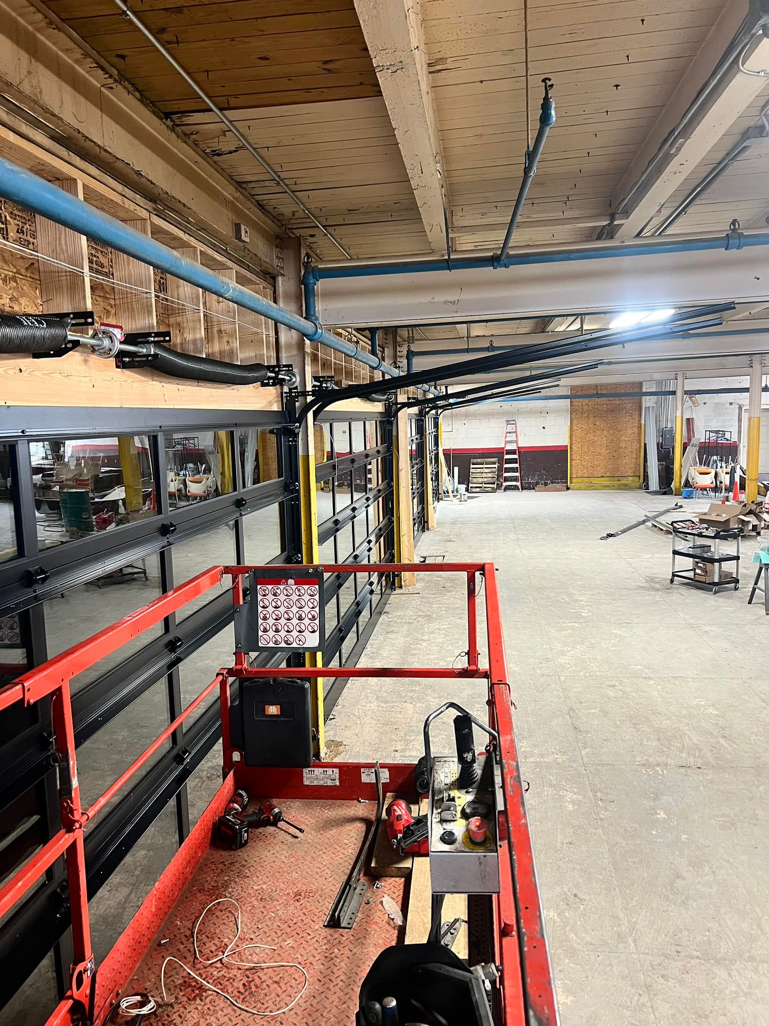 A large warehouse with a red lift in the middle of it.