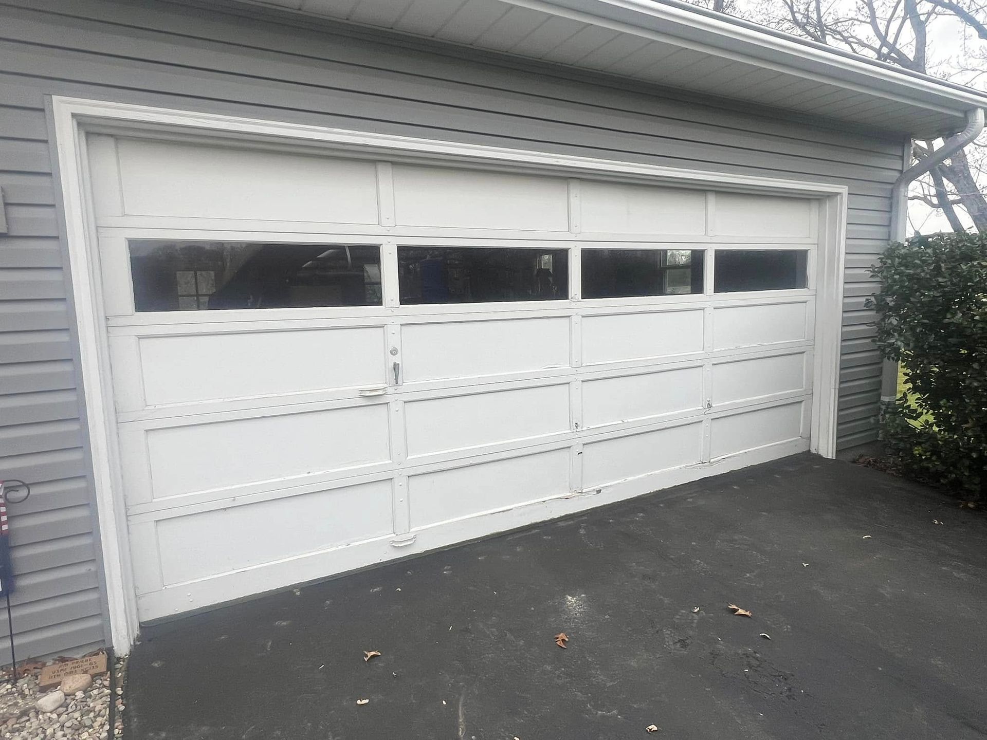 A white garage door is sitting in front of a house.