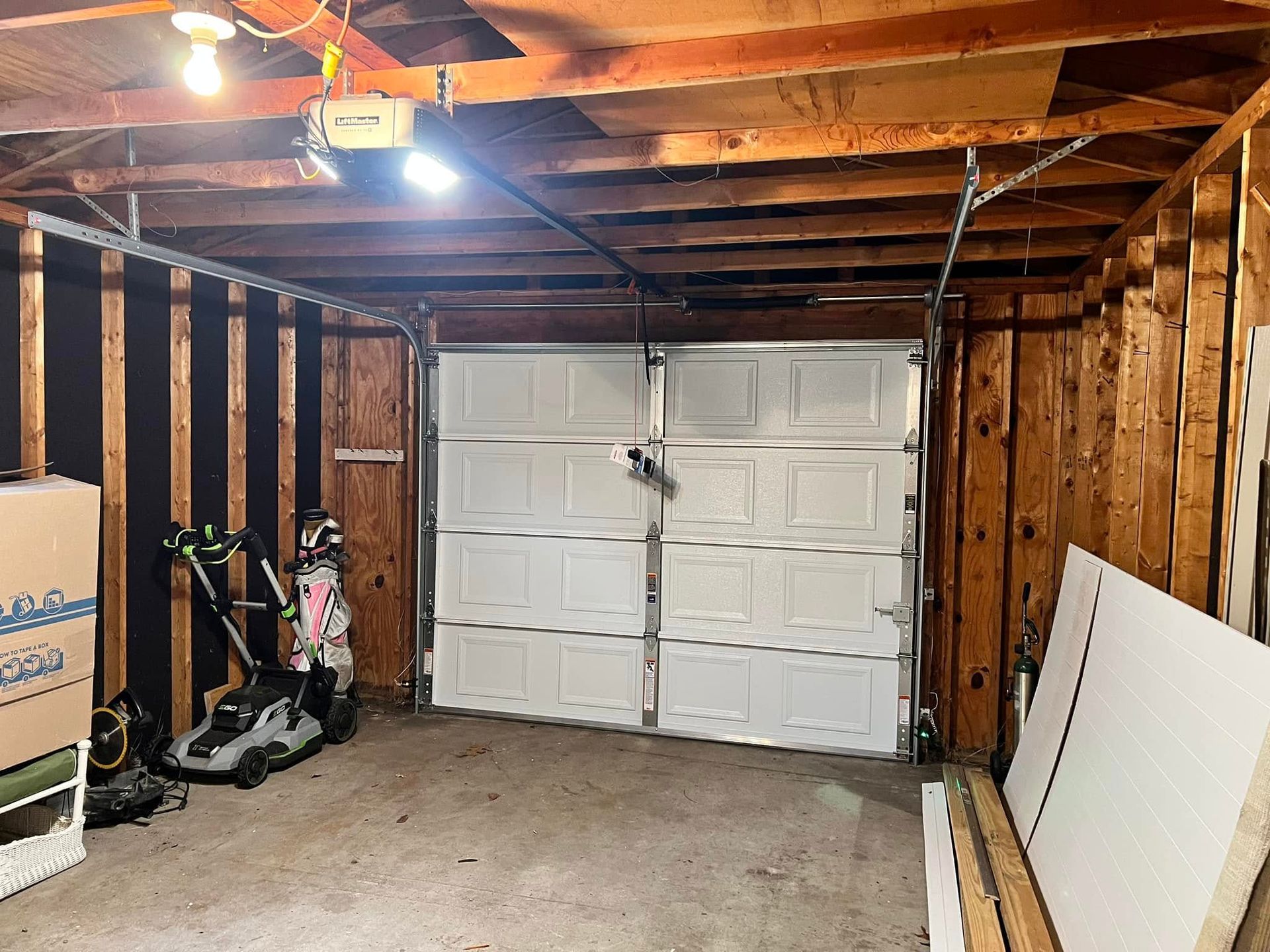 A garage with a white garage door and a scooter in it.