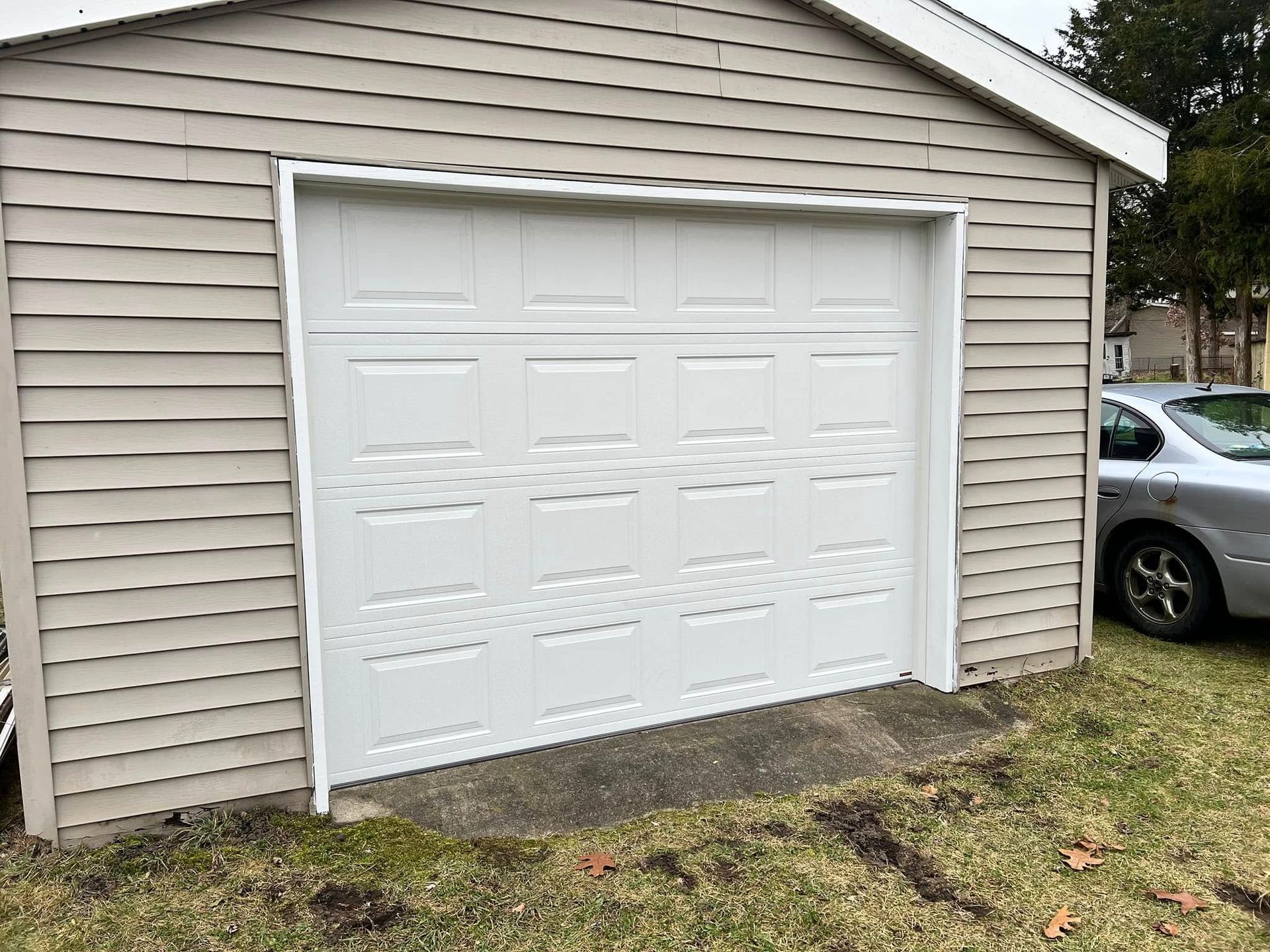 A white garage door with a car parked in front of it.