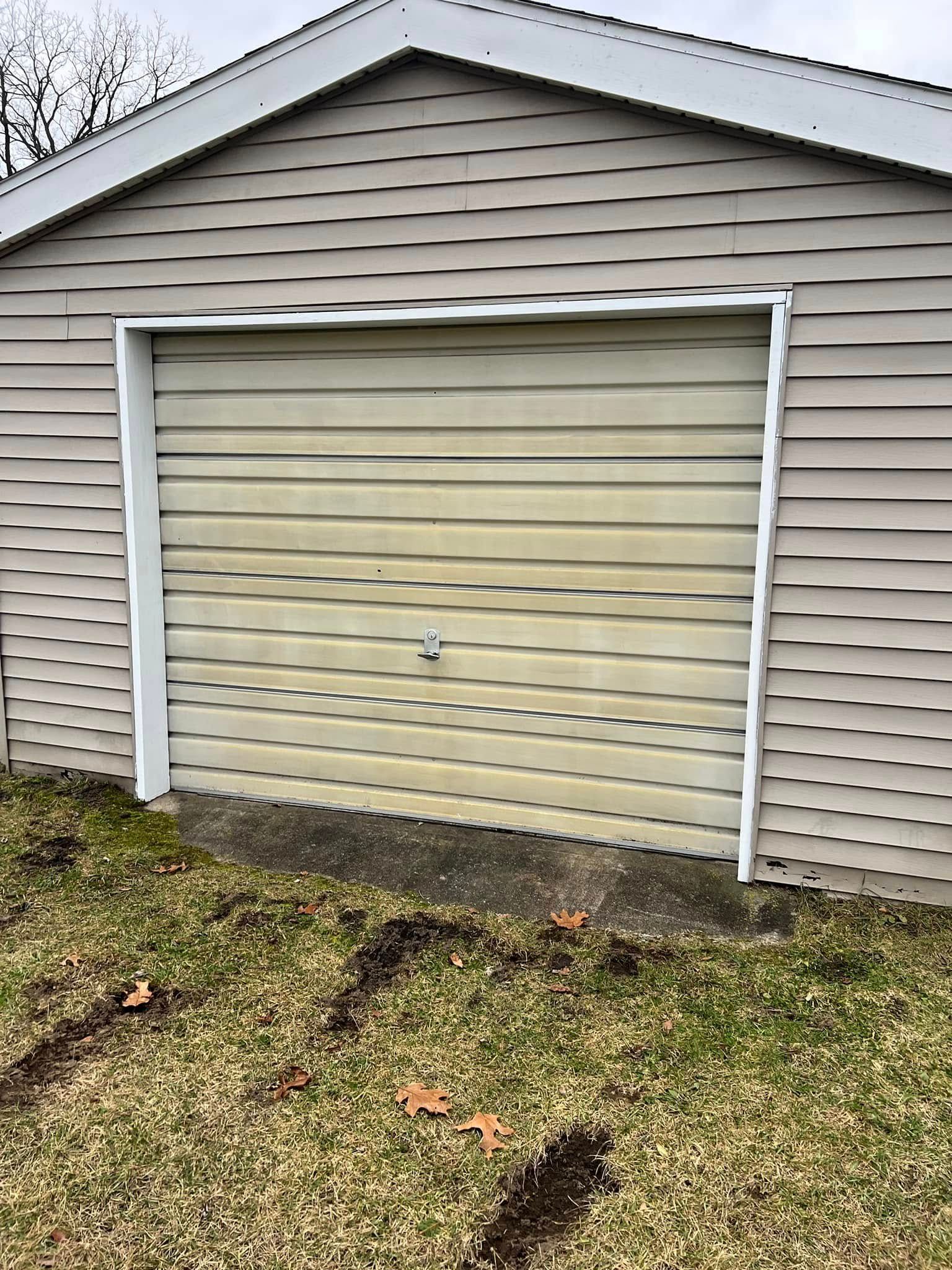 A garage door is sitting in the grass next to a house.
