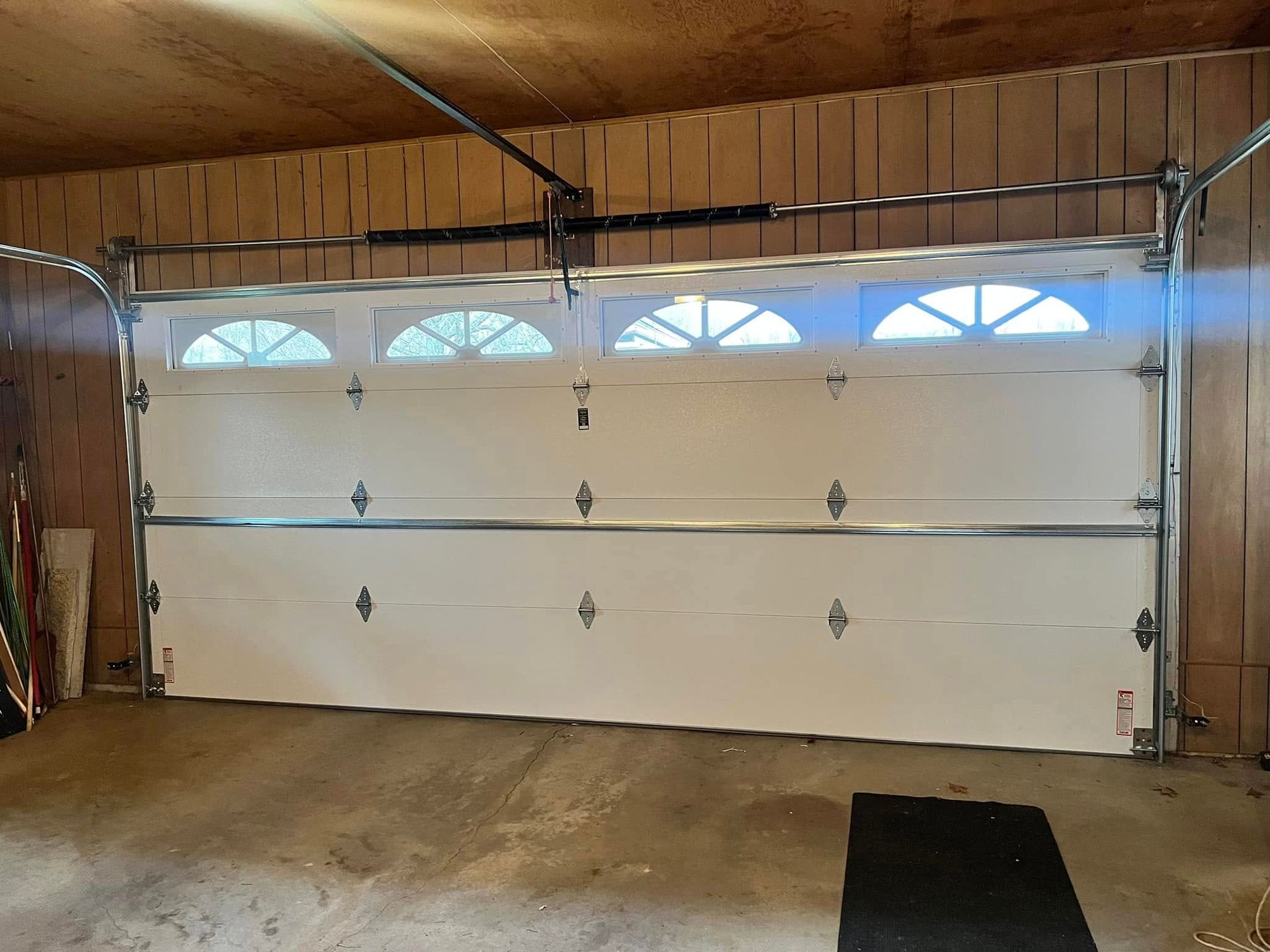 A large white garage door is open in a garage.