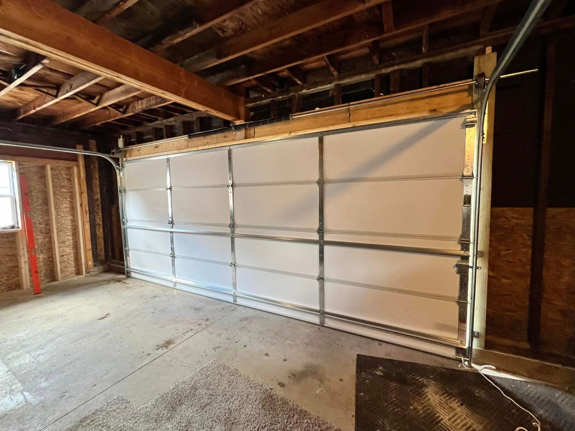 A large white garage door is open in a garage.