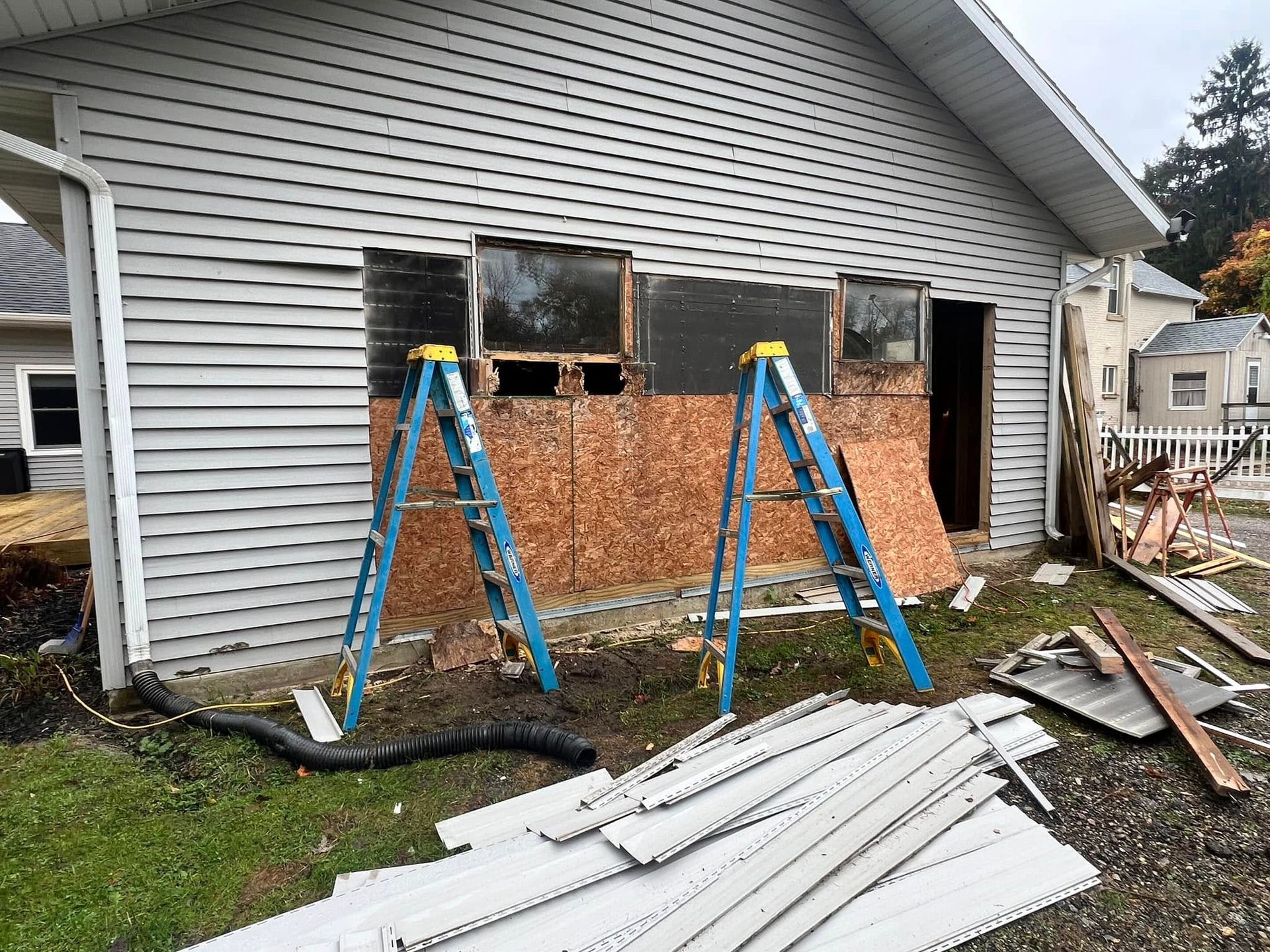 Two ladders are sitting in front of a house that is being remodeled.
