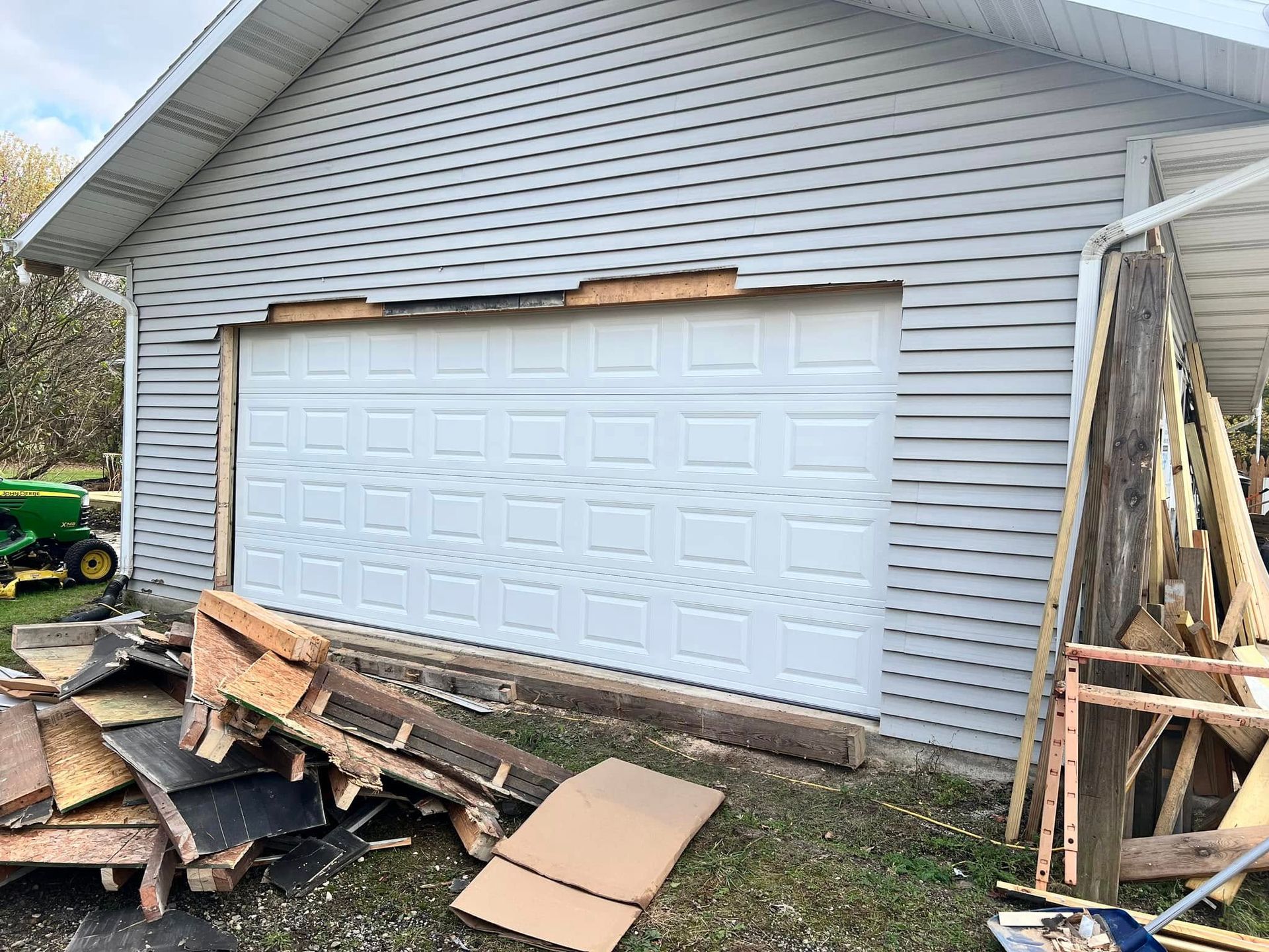A white garage door is being removed from a house.