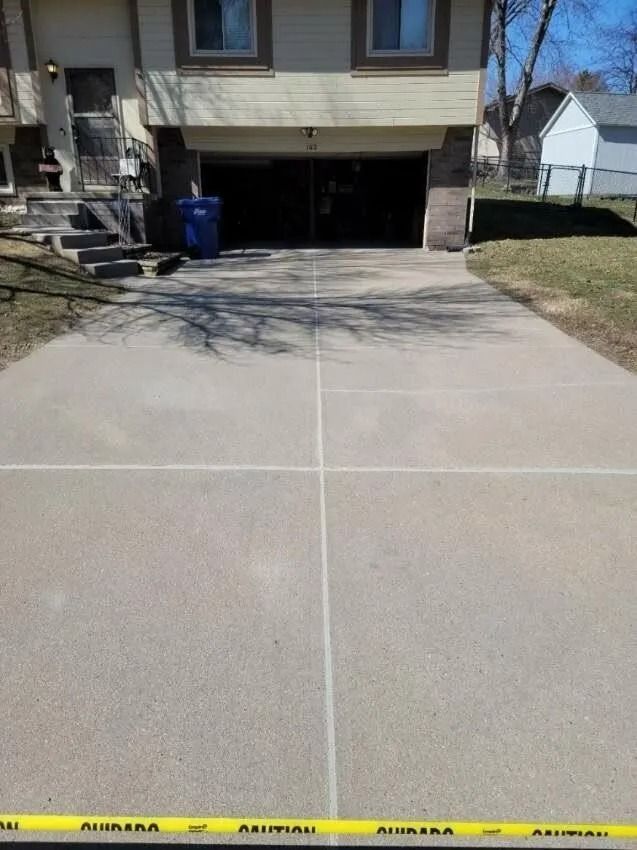 Driveway in front of a house, with white lines marking sections. Caution tape across the bottom.
