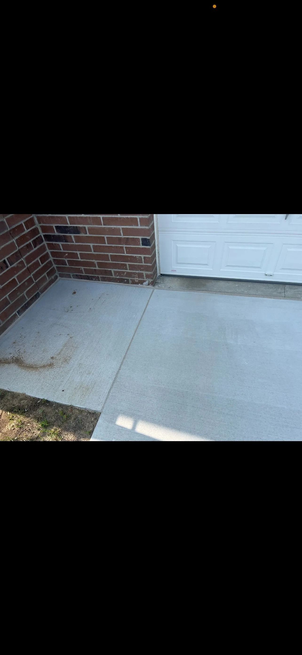 Brick wall and white garage door next to a concrete surface.