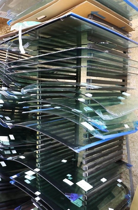 Stacked sheets of glass on a warehouse shelf, with reflections and blue-edged panes visible