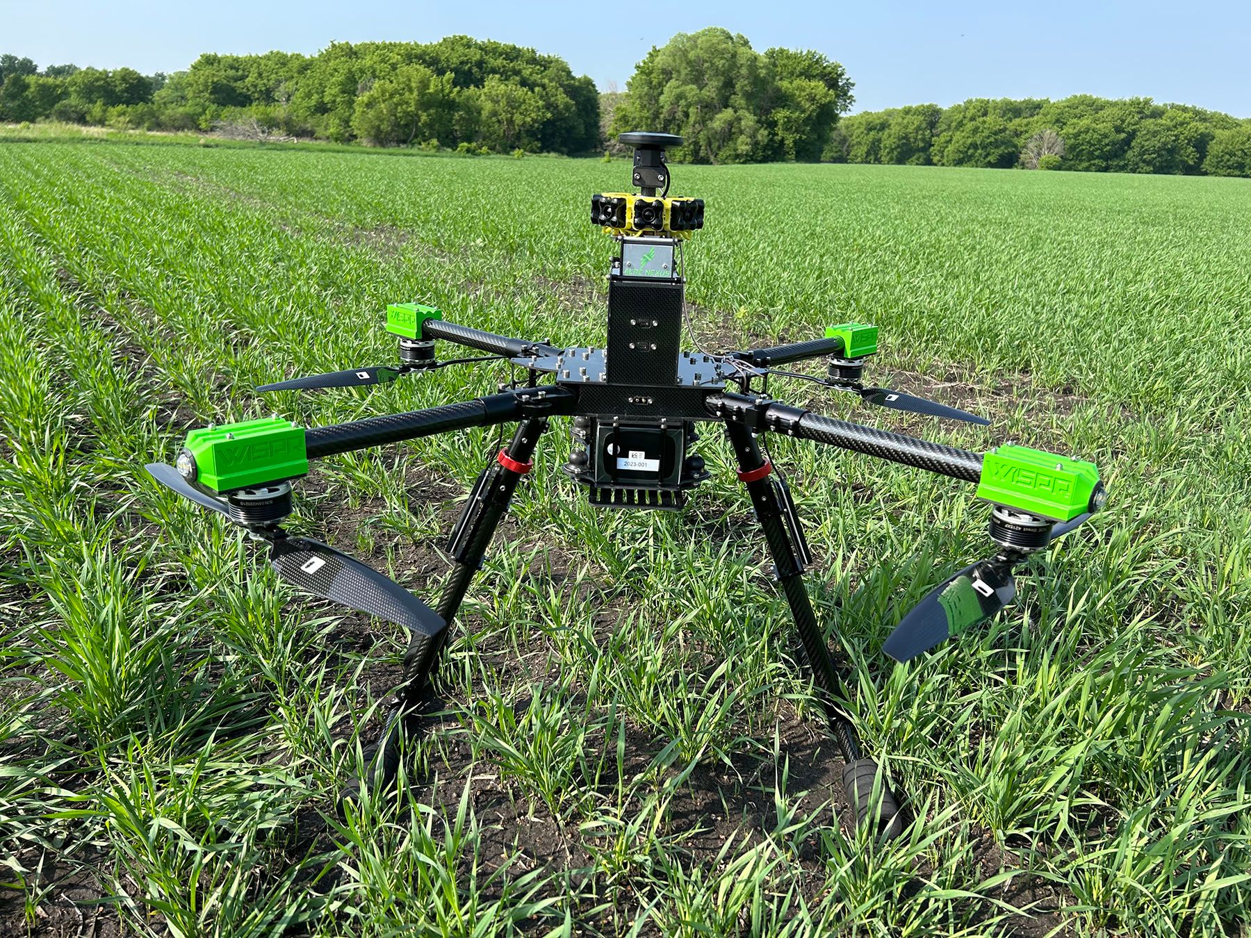 A drone is sitting in the middle of a grassy field.