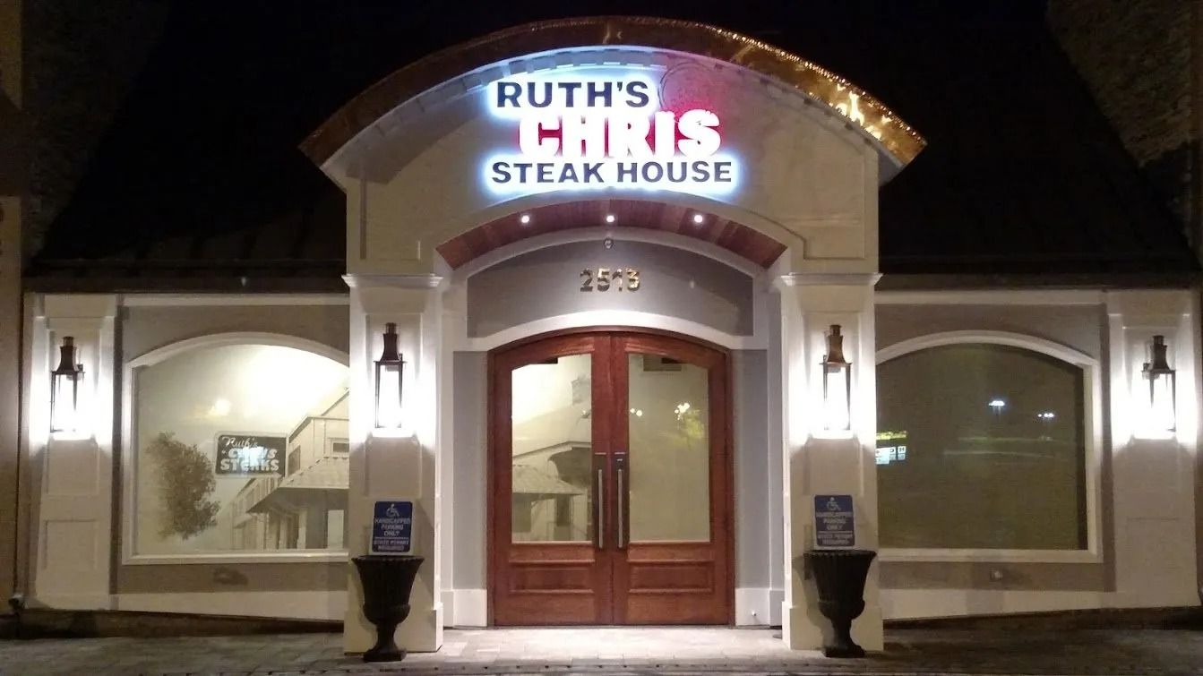 Ruth's Chris Steak House entrance at night with illuminated sign and ornate facade.