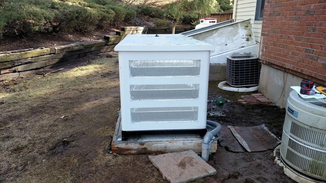 White generator on concrete pad next to a brick house and HVAC unit in a backyard.