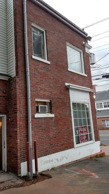 Red brick building with a few windows, a downspout, and an air conditioner.