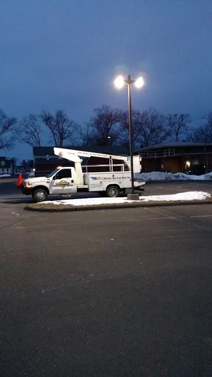 Utility truck parked near a street lamp in a snowy lot at dusk.