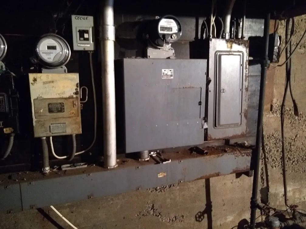Electrical boxes and meters on a concrete wall. Gray metal boxes and pipes with wear.