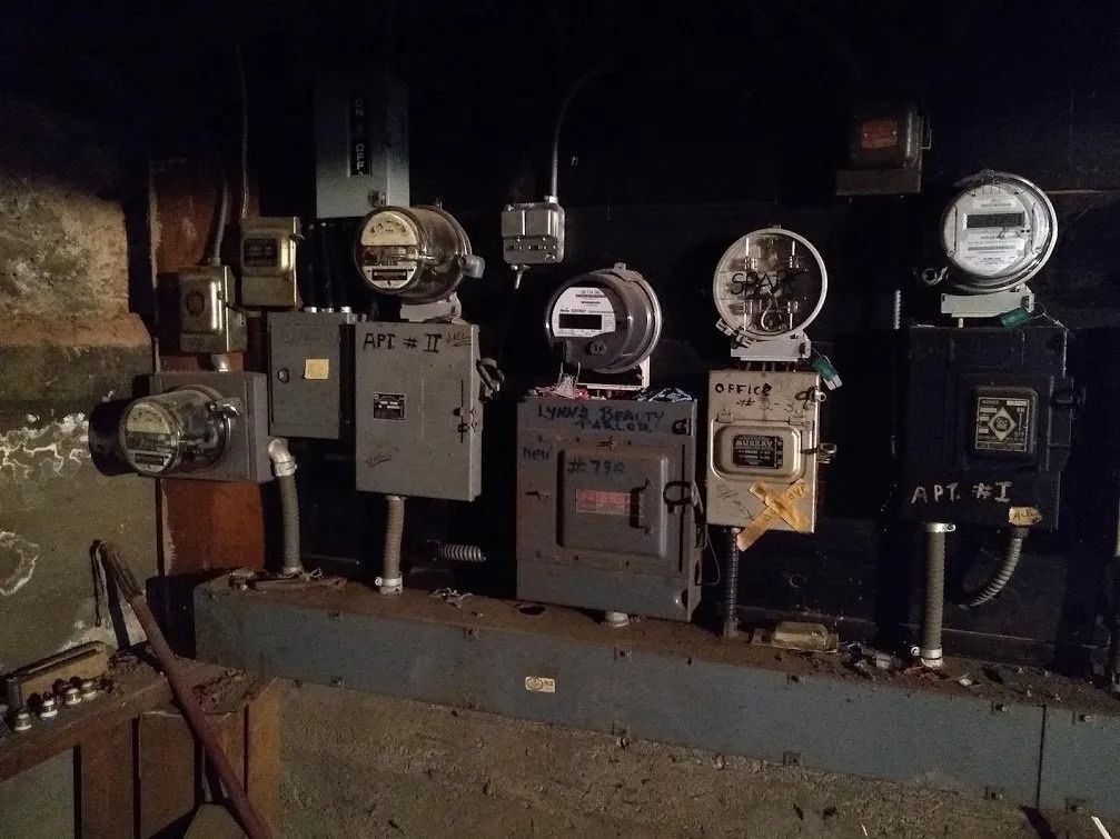 Electrical meters and boxes mounted on a dark, industrial wall.