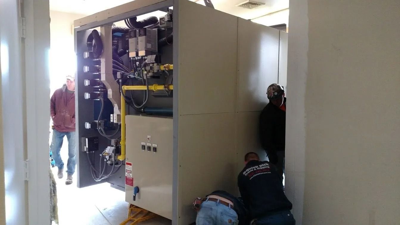 Workers install a large industrial machine in a room.