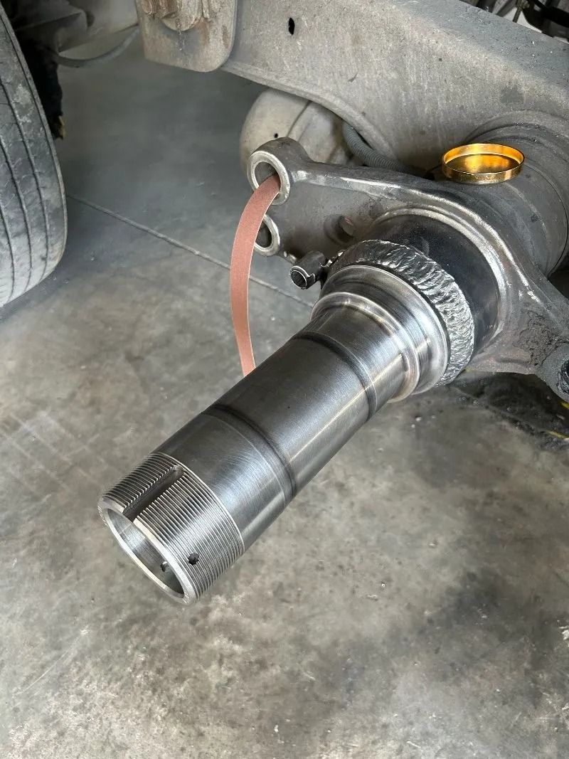 Car wheel hub and axle stub exposed in a garage, with a red strap hanging nearby.