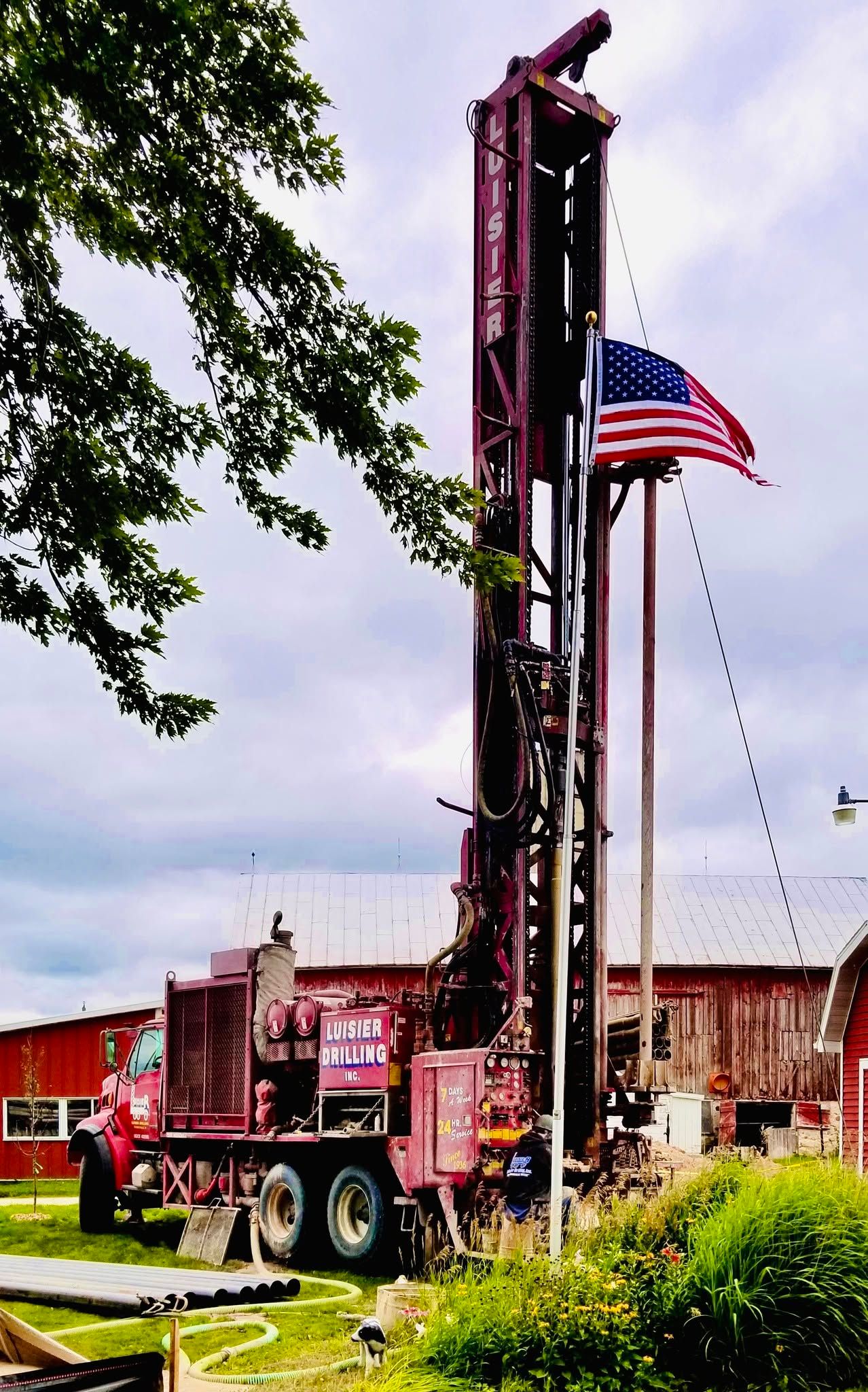 Drilling rig beside a red truck flying an American flag at a construction site