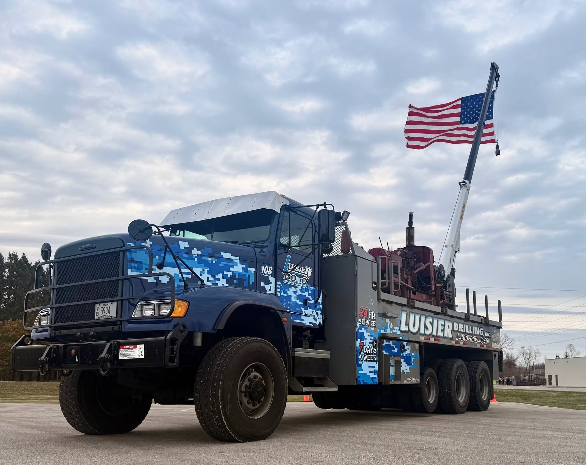 Blue Louisiana tow truck with American flag parked outdoors under cloudy sky