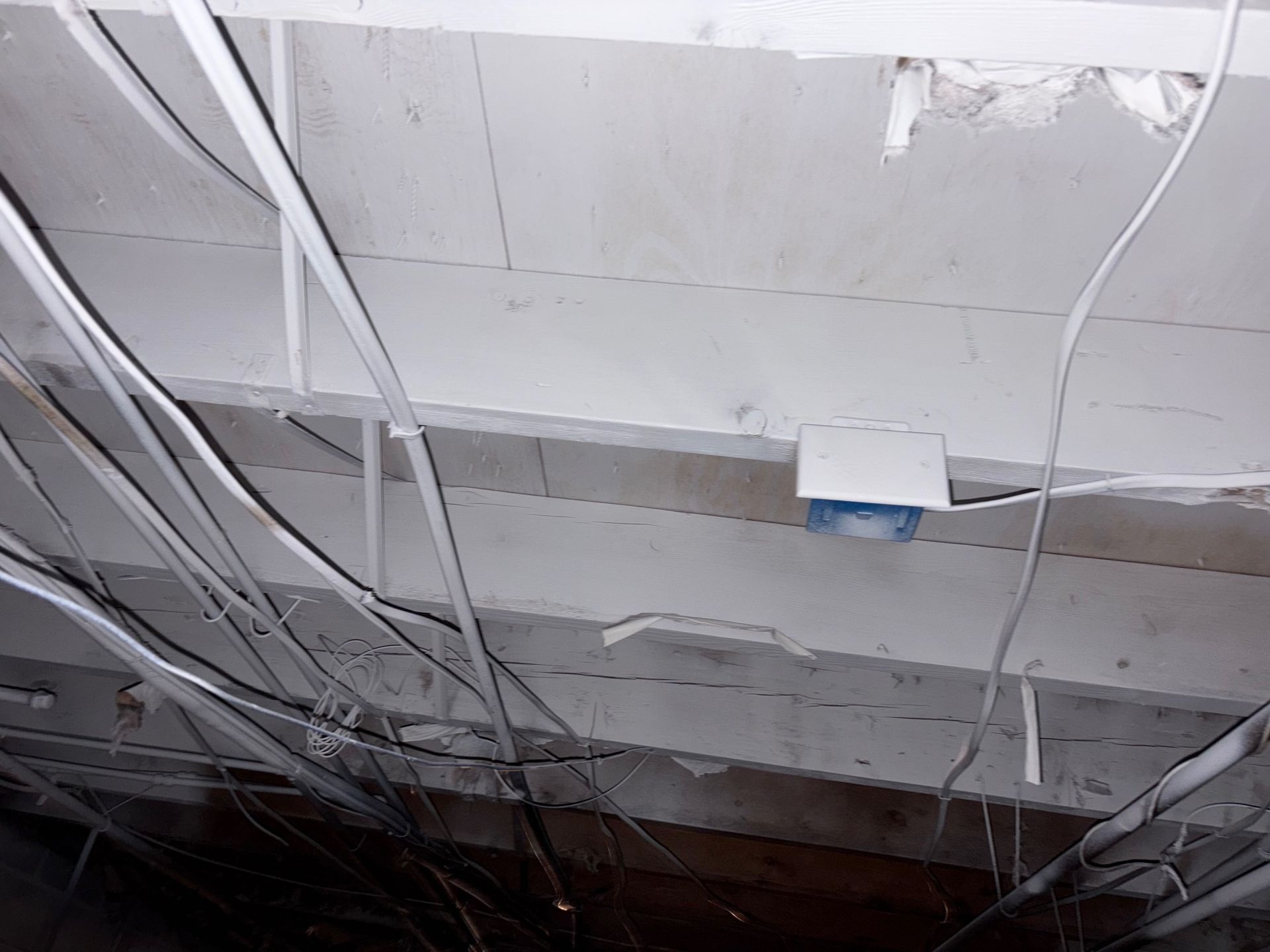 Ceiling with exposed wiring, painted white beams, and a mounted electrical box.