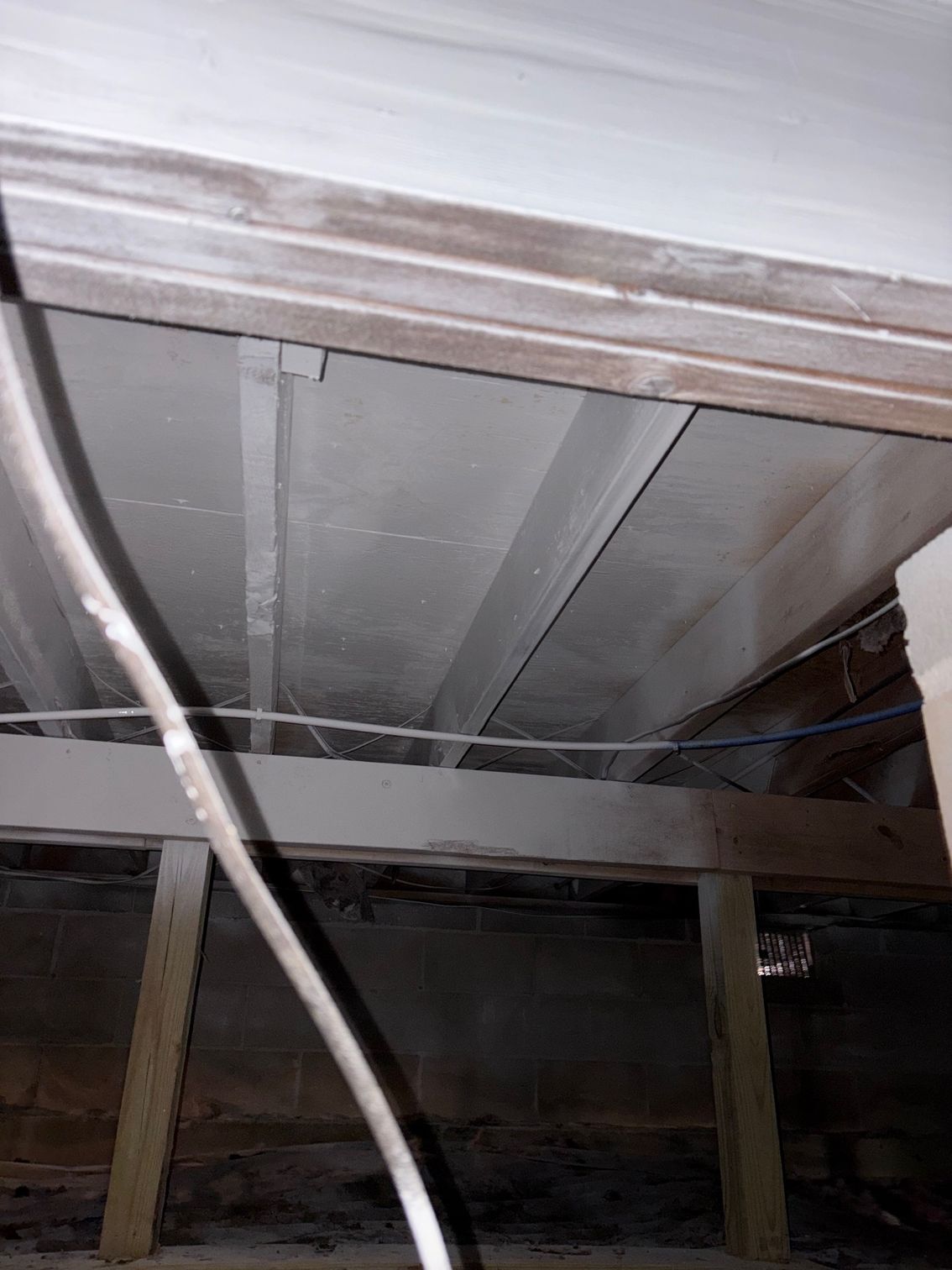View of a crawl space ceiling with wooden beams, electrical wiring, and a cable.