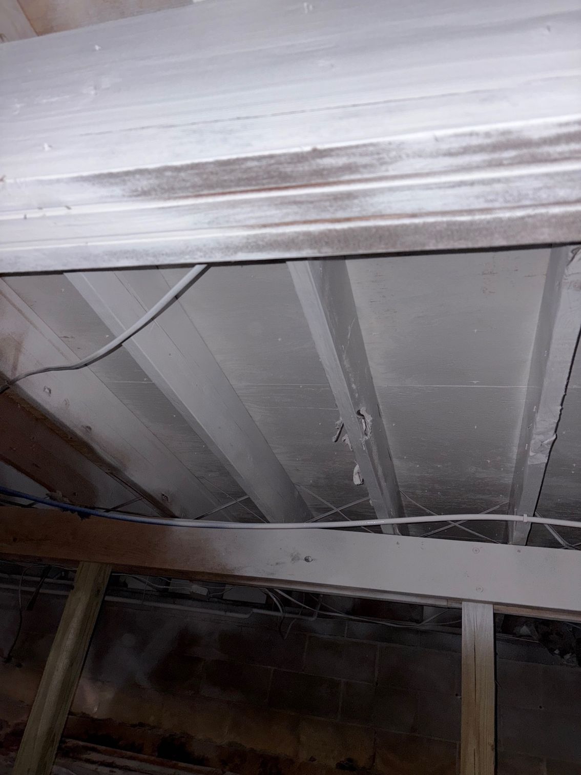 White ceiling with water damage and exposed wooden beams.