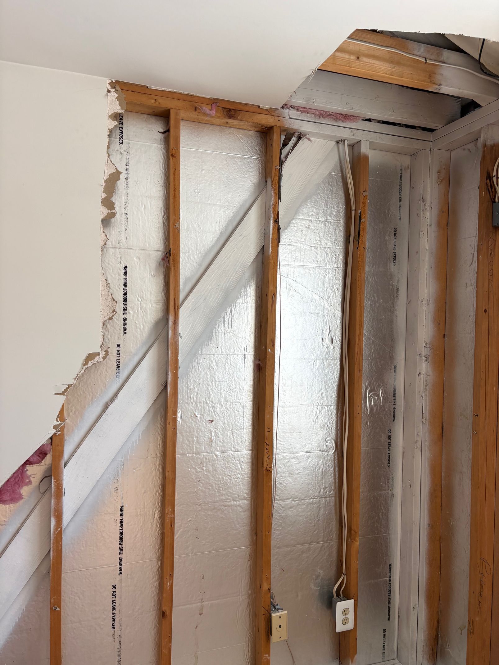 Interior wall framing exposed, showing insulation and wiring.