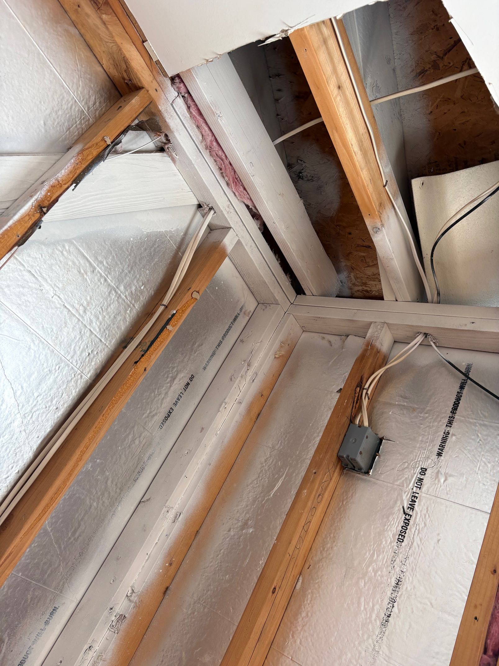 Interior view of an attic space with wooden beams and reflective insulation.