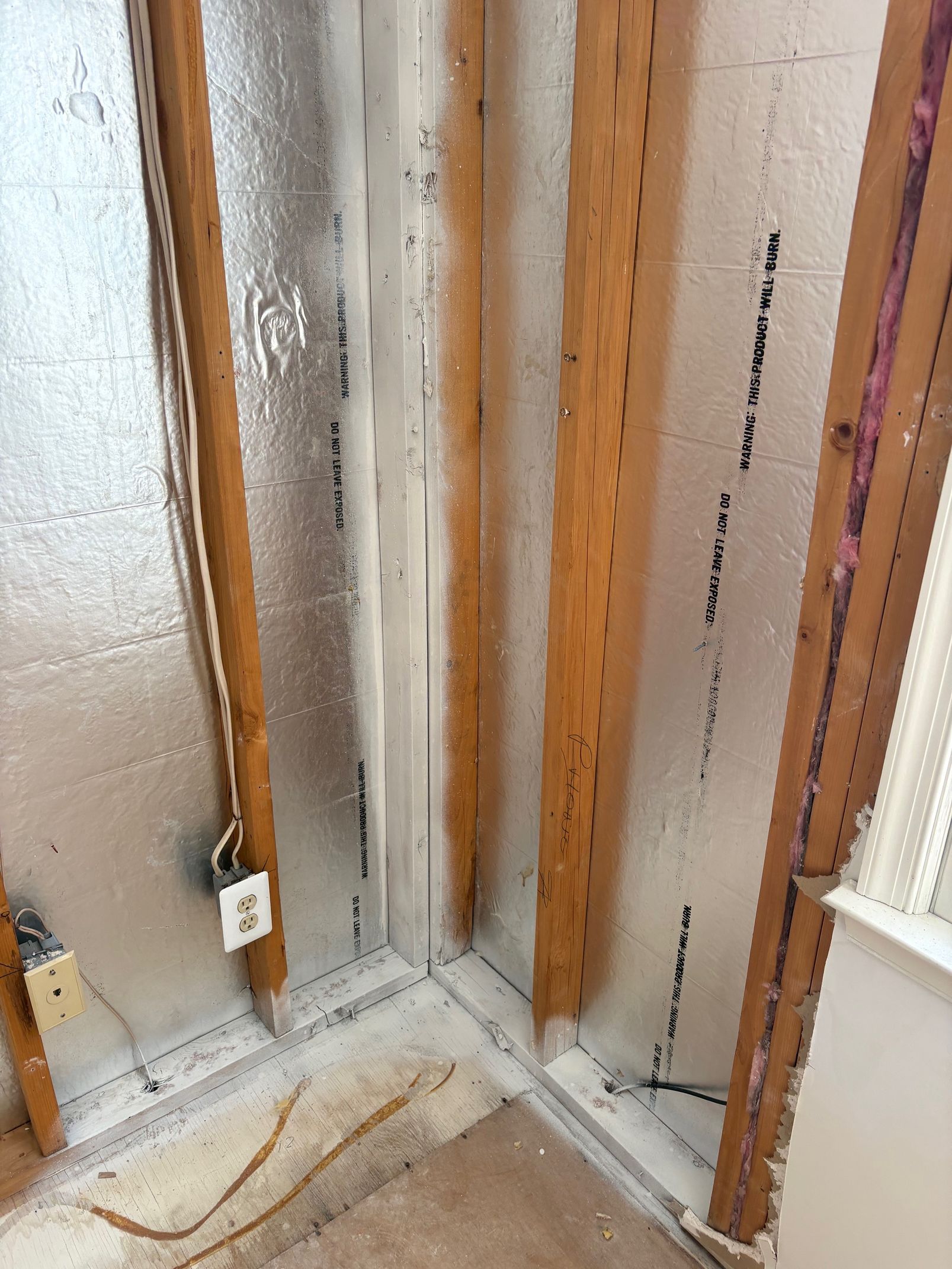 Interior wall framing with insulation, electrical outlet, and corner.