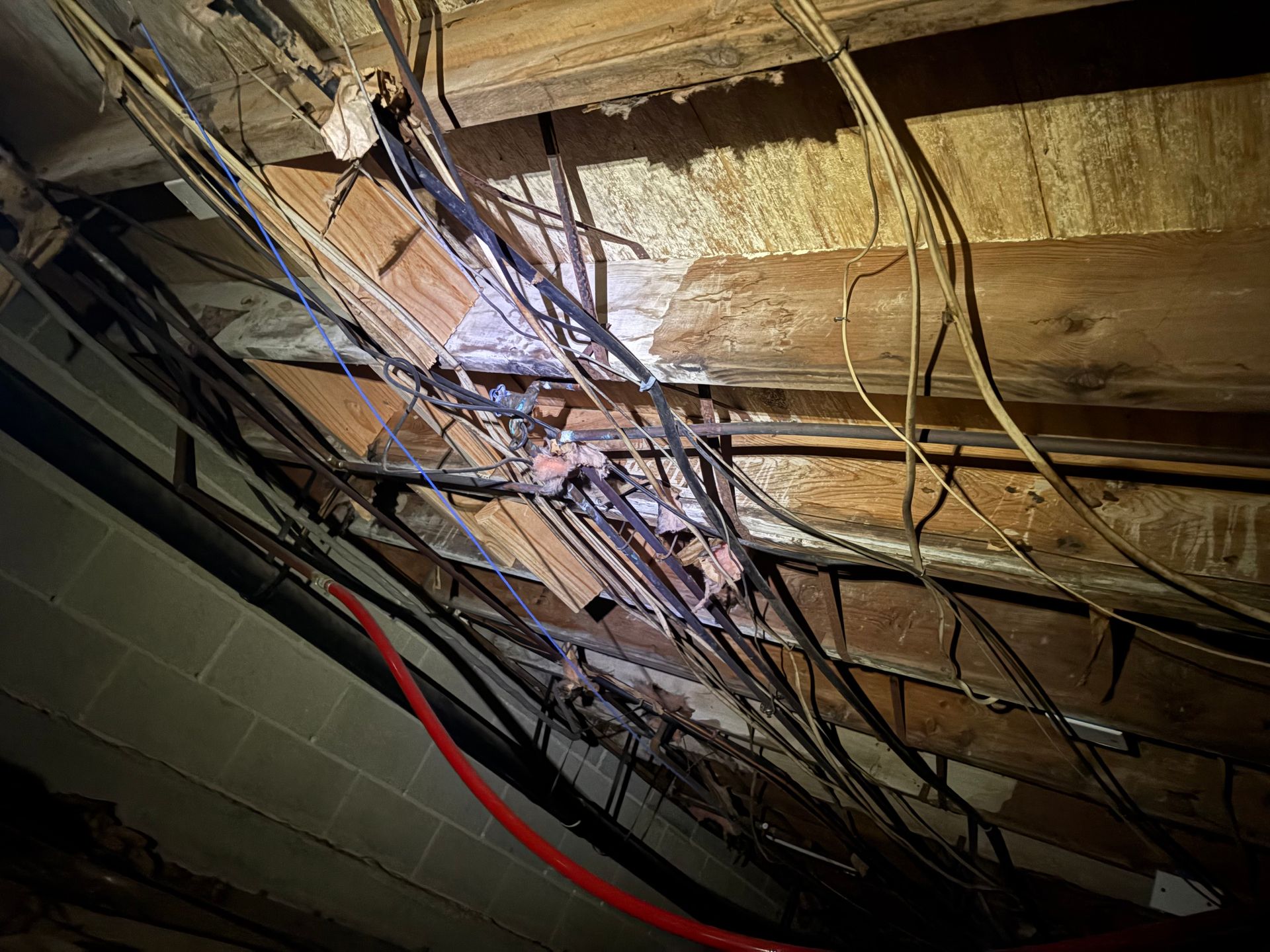 Overhead view of tangled electrical wires and a damaged wooden structure.