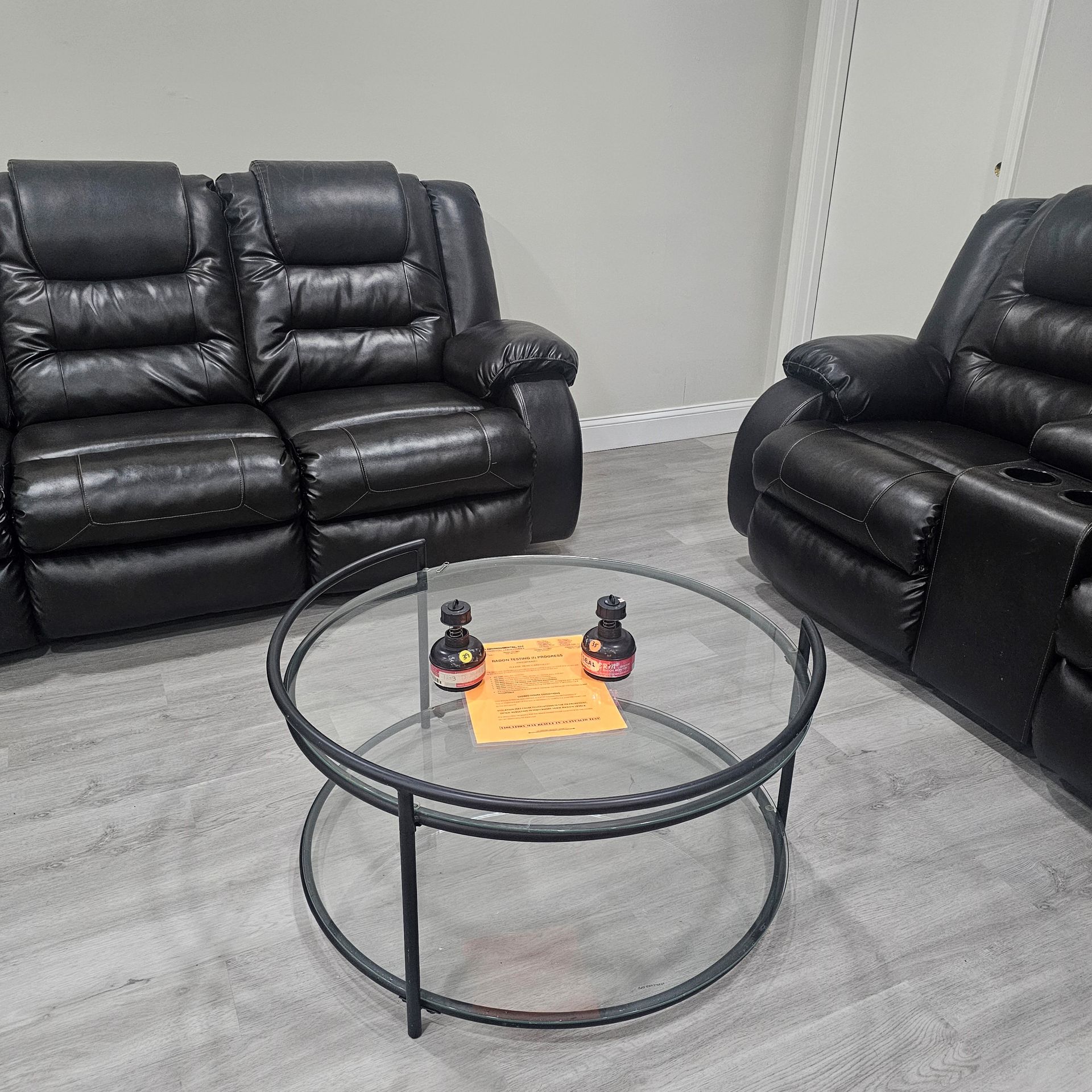 Black leather reclining furniture in a room with a glass coffee table.