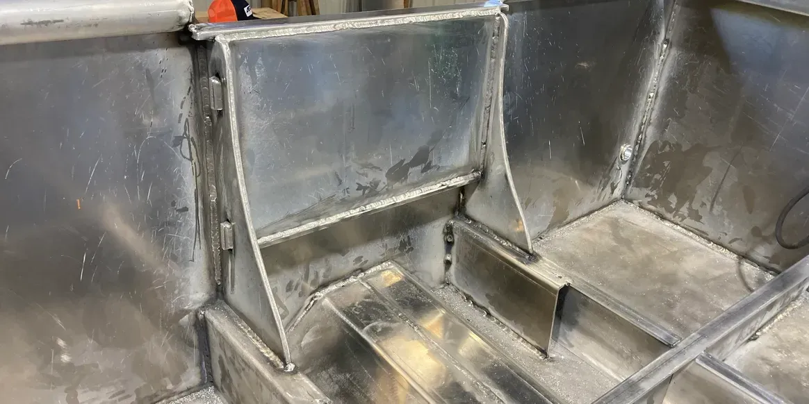 Welded aluminum interior structure of a boat hull, showing reinforced bracing and metal framework.