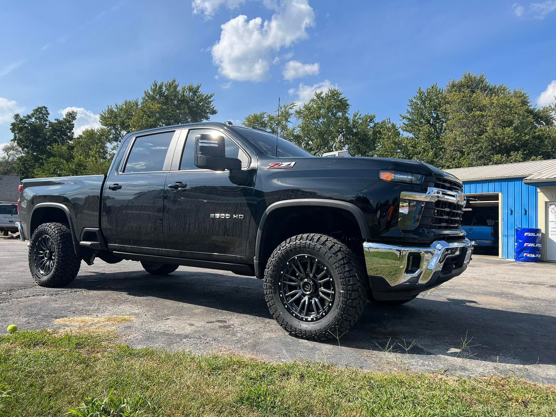 A black truck is parked on the side of the road in front of a building.