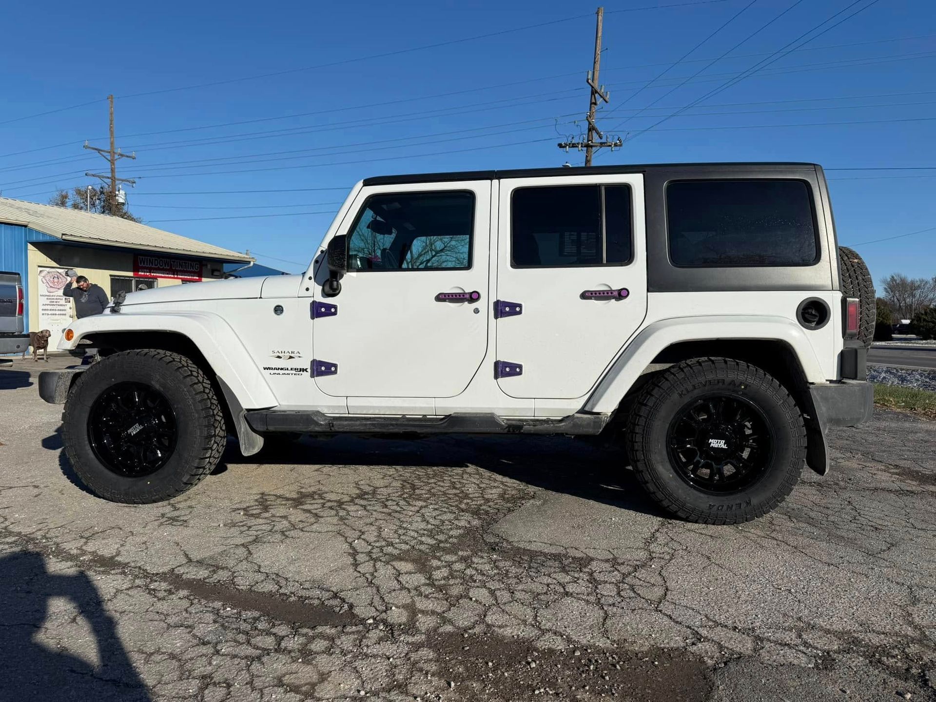 A white jeep wrangler is parked in a parking lot.