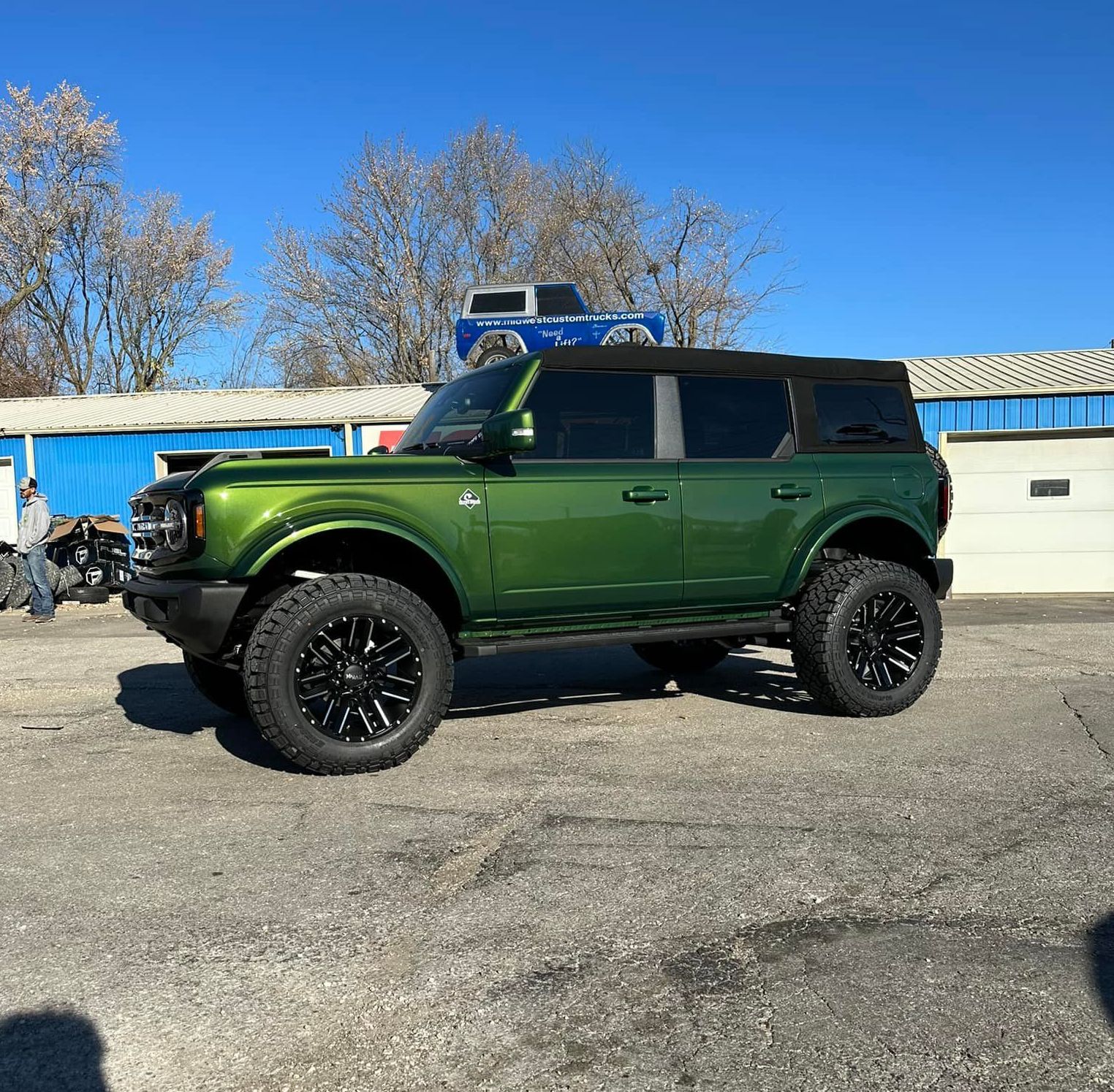 A green ford bronco is parked in a parking lot.